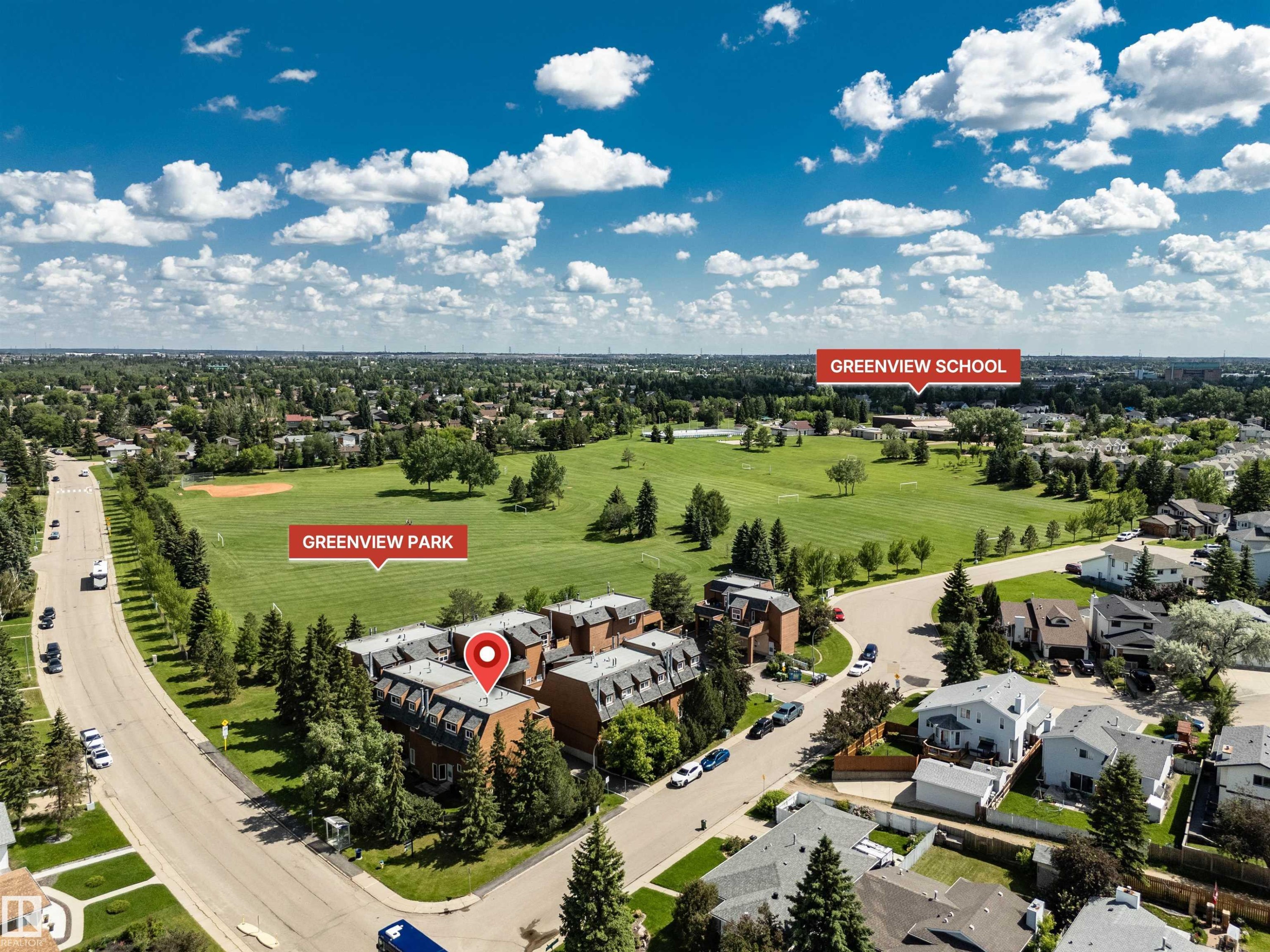 Aerial overview showcasing a multi-unit residential building with multiple levels, surrounded by mature trees - 5953 40 Avenue, Edmonton, AB