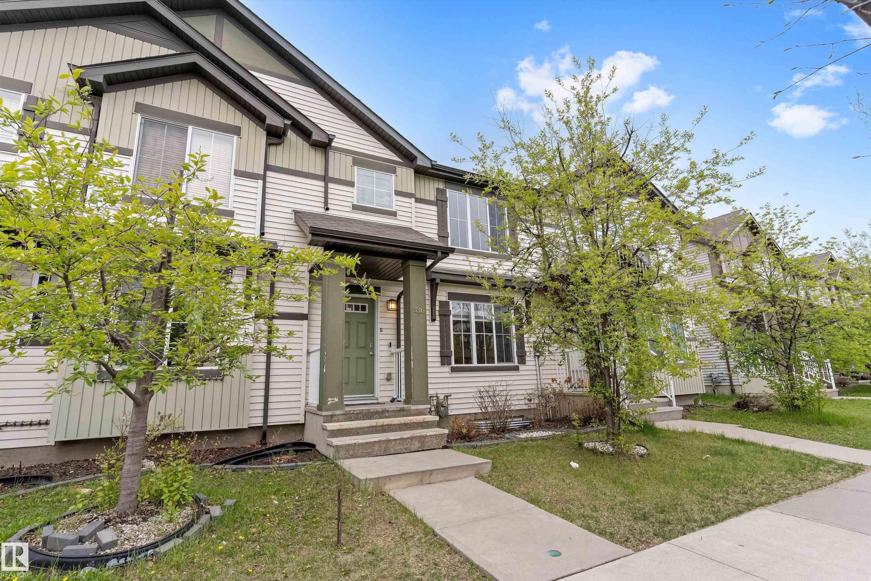 Multi-level residential exterior featuring light-colored siding with dark trim accents - 336 Watt Boulevard, Edmonton, AB - Outdoor