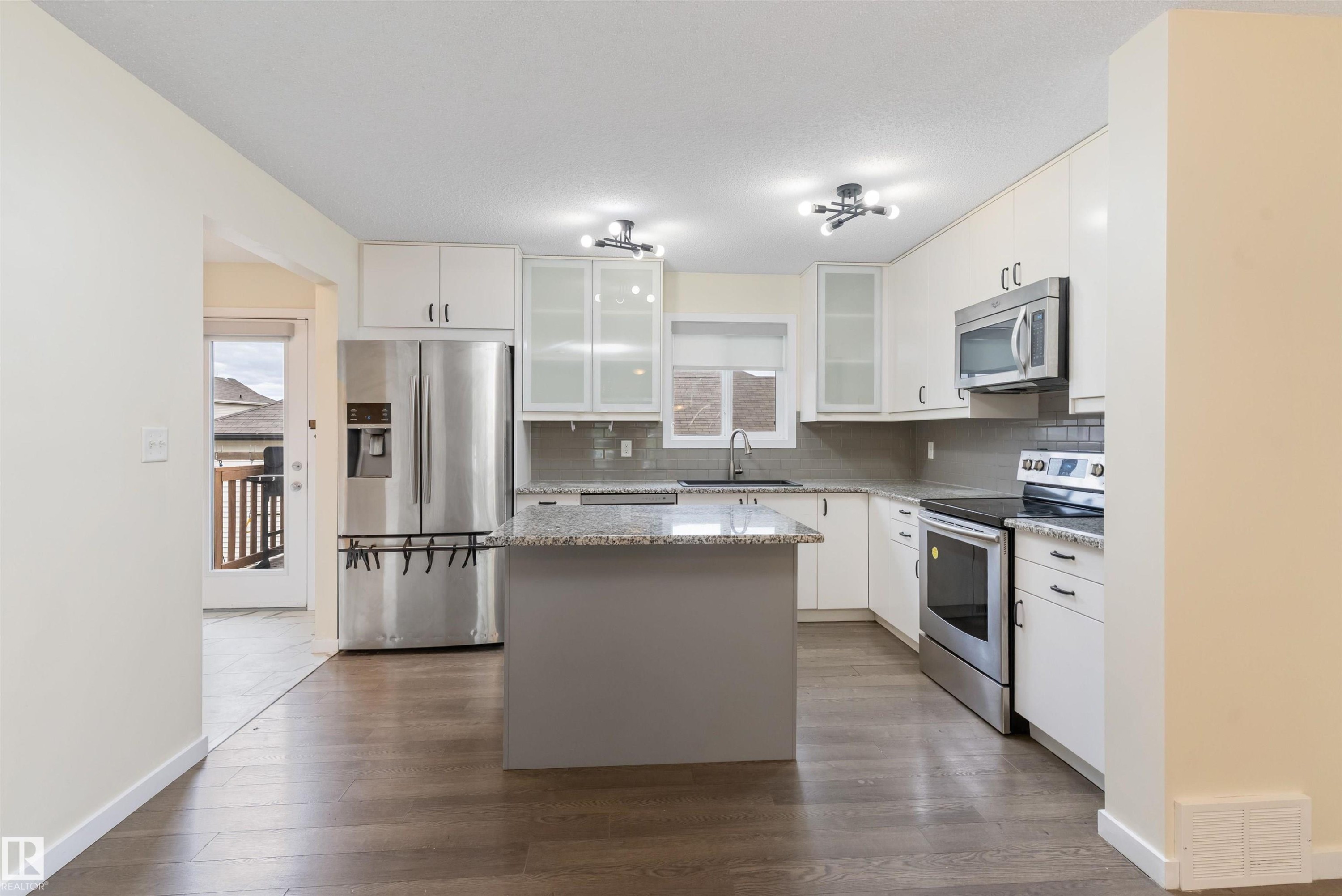 Modern kitchen featuring wood-finish flooring, white cabinetry, and stainless steel appliances - 336 Watt Boulevard, Edmonton, AB - Indoor Photo Showing Kitchen