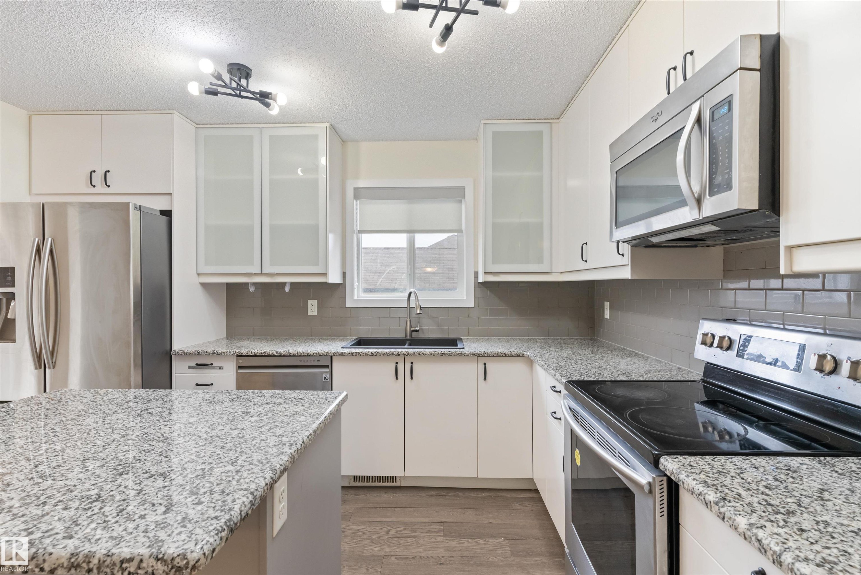 Kitchen featuring white cabinetry, granite countertops, stainless steel appliances, a subway tile backsplash, and wood-finish flooring - 336 Watt Boulevard, Edmonton, AB - Indoor Photo Showing Kitchen With Upgraded Kitchen