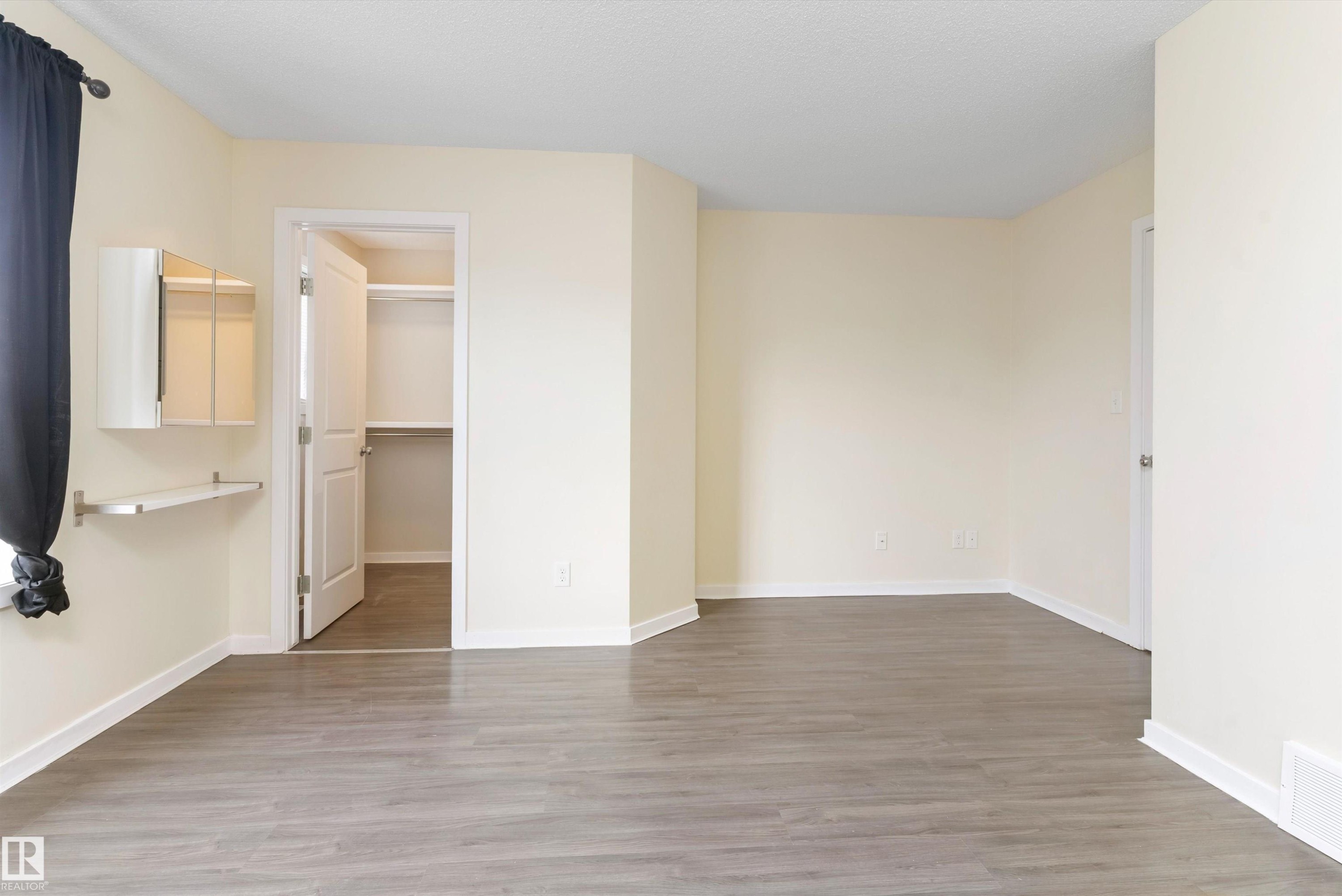 Spacious room featuring wood-finish flooring, light-toned wall finishes, and a built-in wall cabinet with an integrated shelf - 336 Watt Boulevard, Edmonton, AB - Indoor Photo Showing Other Room