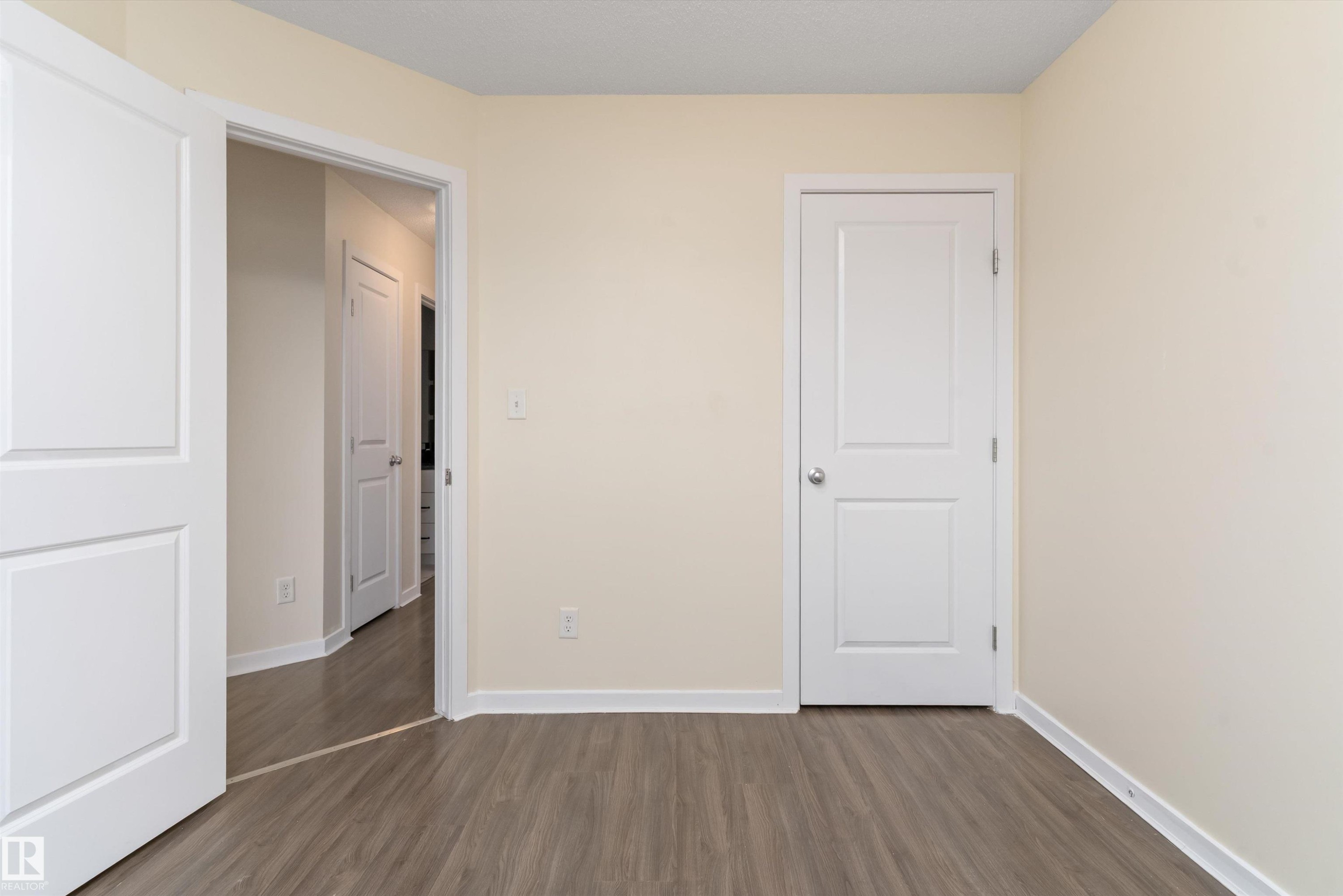 Room featuring wood-finish flooring, light-colored walls, white baseboards, and two white paneled doors - 336 Watt Boulevard, Edmonton, AB - Indoor Photo Showing Other Room