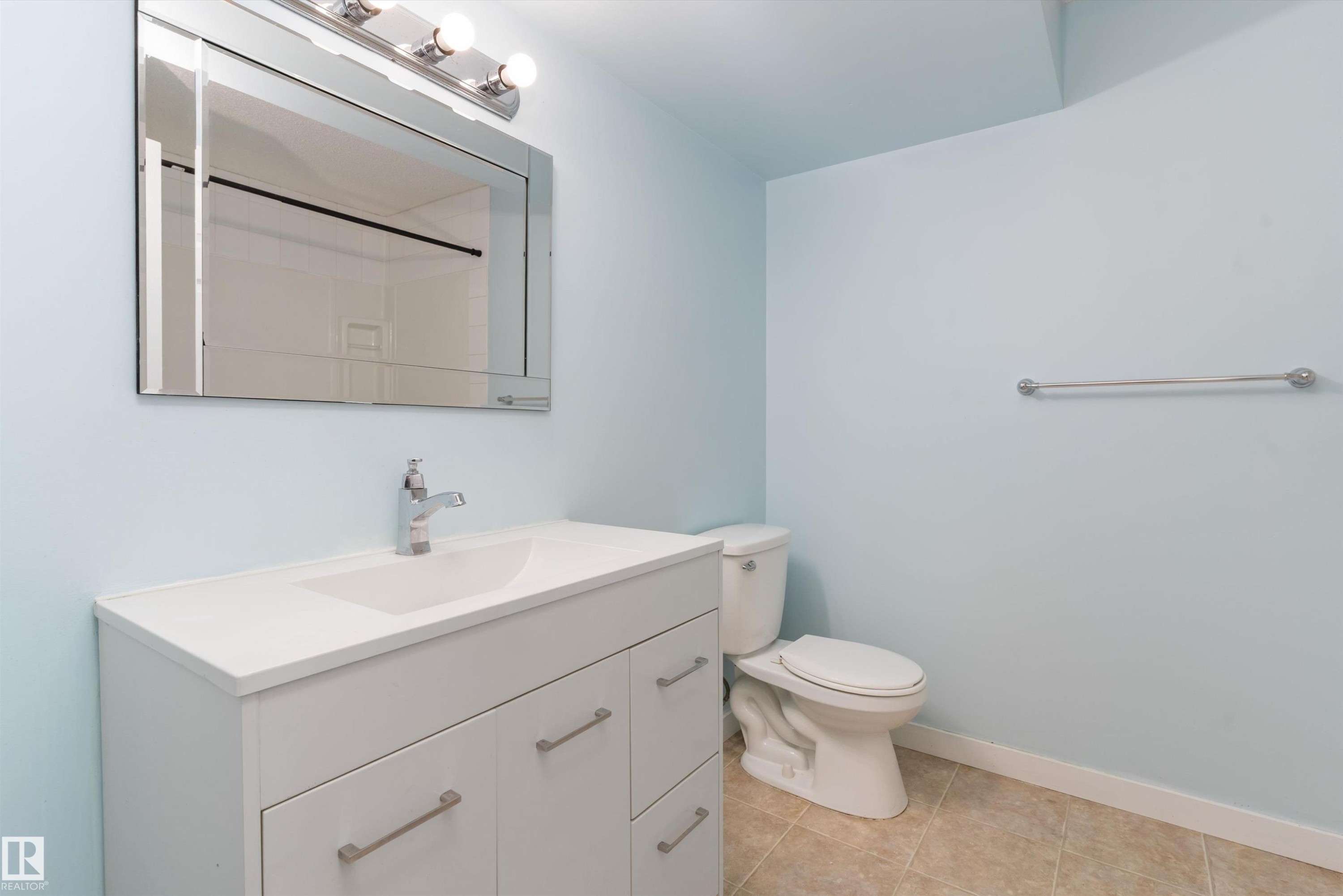 Bathroom featuring a modern white vanity with an integrated sink, a chrome faucet, and a large wall-mounted mirror with overhead lighting - 336 Watt Boulevard, Edmonton, AB - Indoor Photo Showing Bathroom