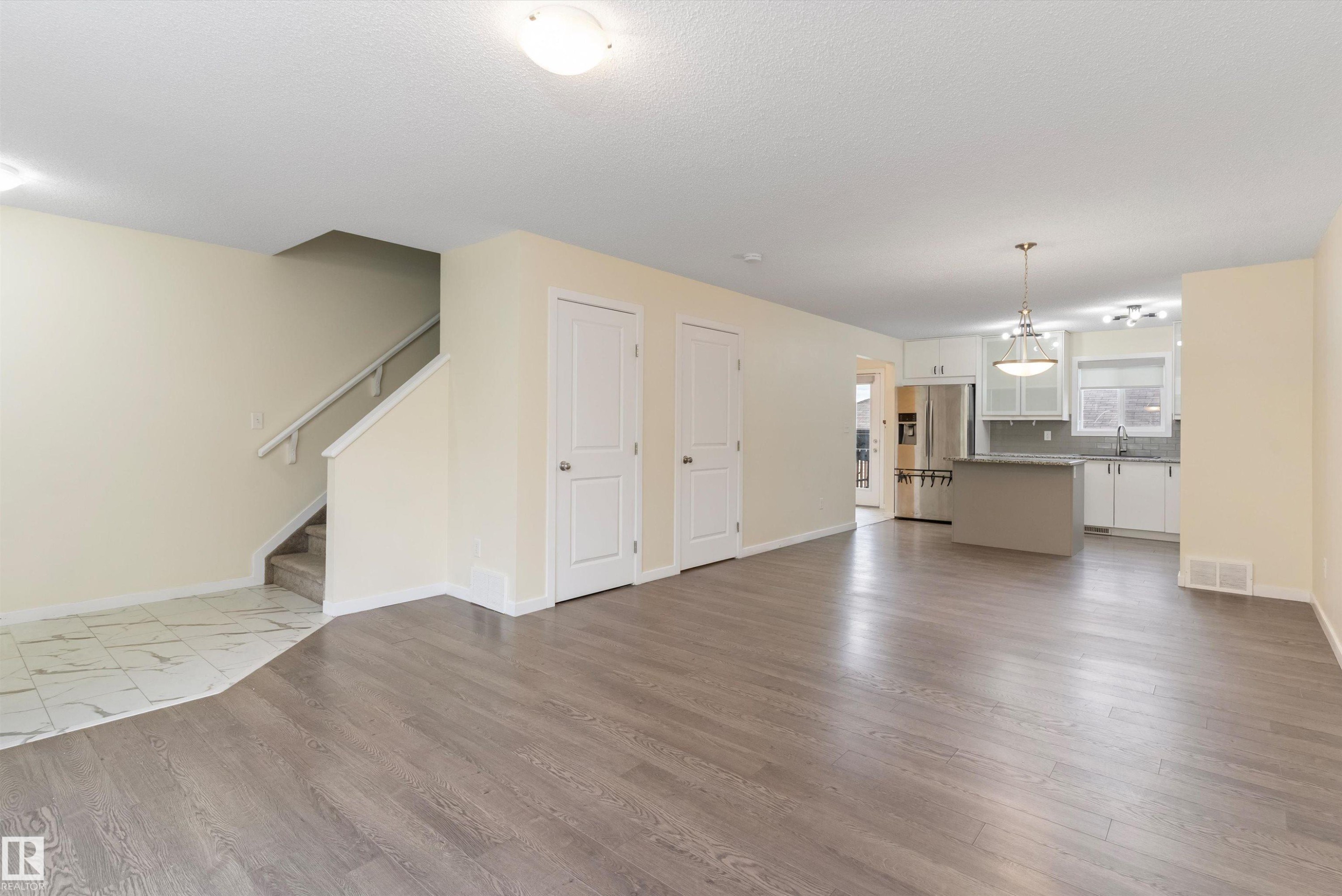 Expansive open-concept living area featuring wood-finish flooring, neutral wall tones, and recessed ceiling lighting - 336 Watt Boulevard, Edmonton, AB - Indoor Photo Showing Living Room