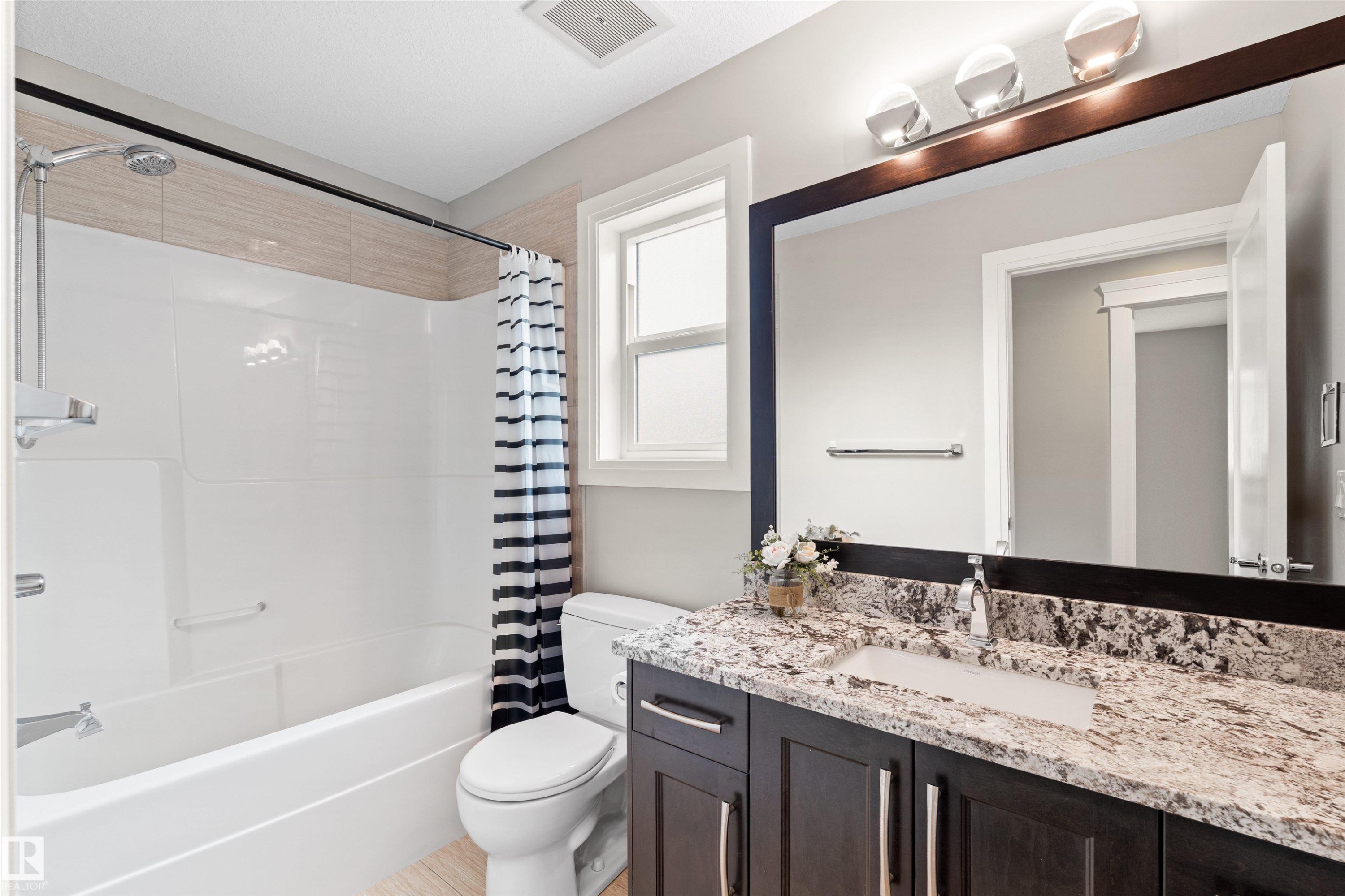 Bathroom featuring a dark wood vanity with a light granite-style countertop, undermount sink, and chrome faucet - 3807 Claxton Close, Edmonton, AB - Indoor Photo Showing Bathroom