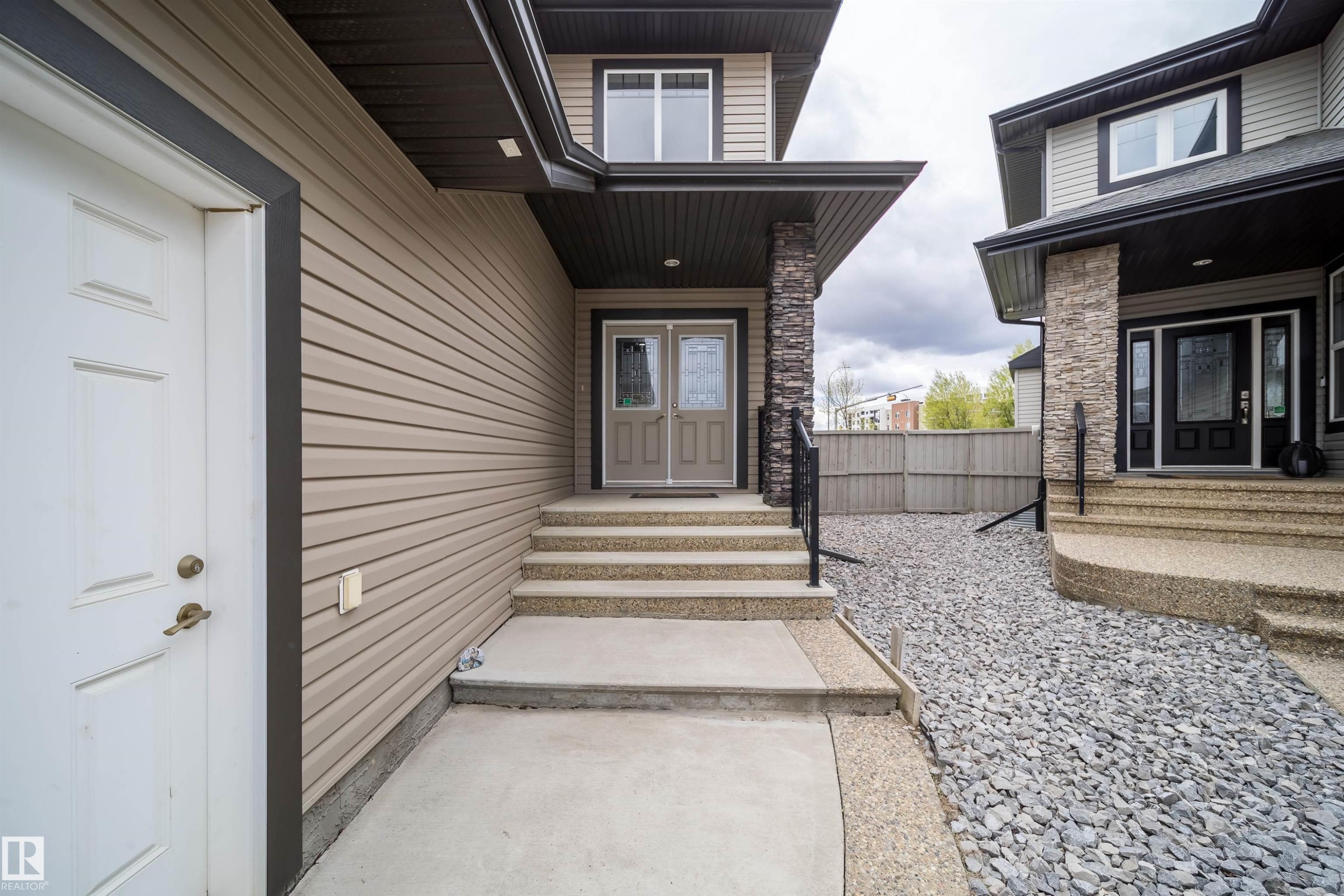Entryway featuring a stone-clad pillar, concrete stairs, and a gravel ground cover - 1508 Cunningham Cape Cape, Edmonton, AB - Outdoor