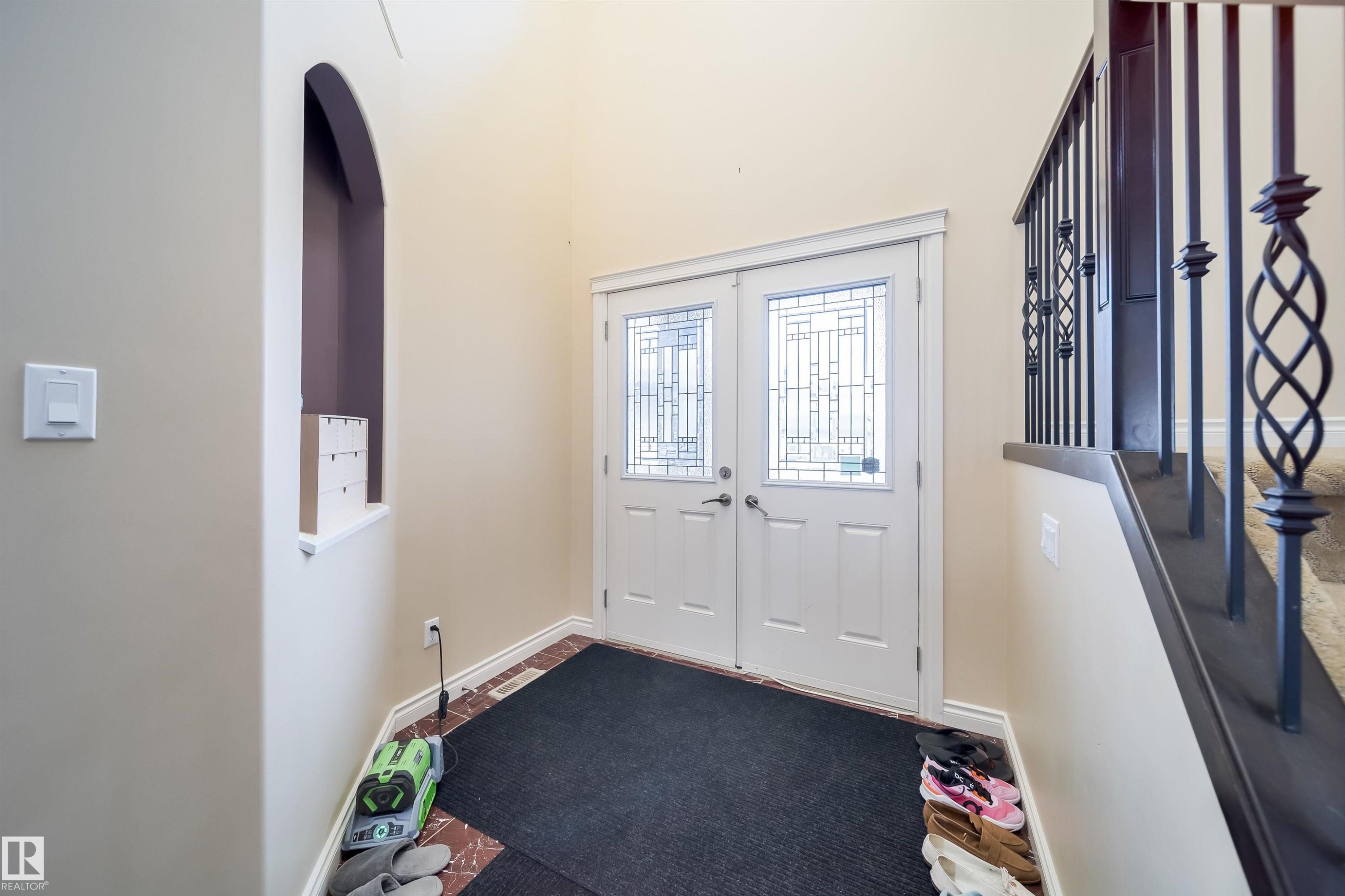 Double entry doors with leaded glass inserts, framed by a decorative arched wall niche - 1508 Cunningham Cape Cape, Edmonton, AB - Indoor Photo Showing Other Room