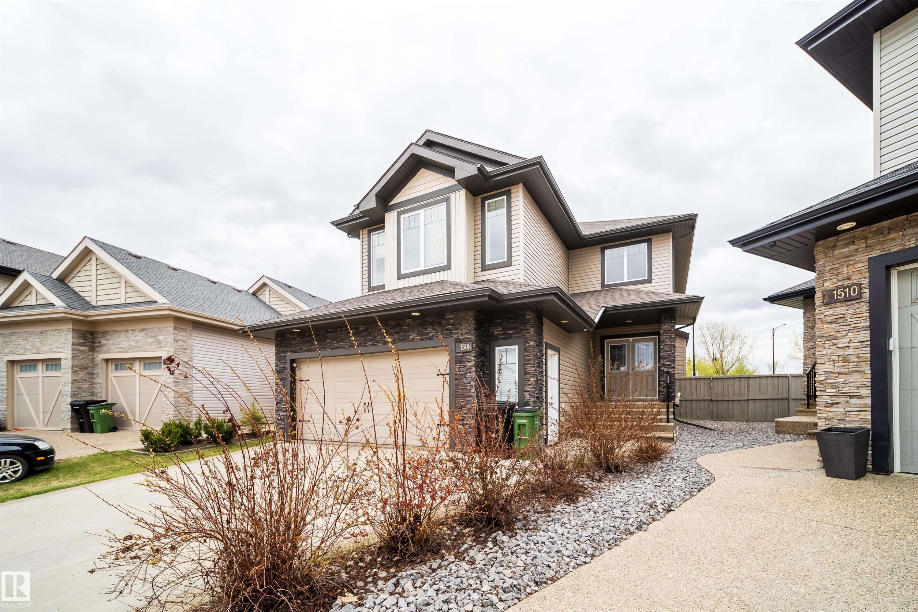 Contemporary two-story residence featuring light-colored siding and dark stone veneer accents - 1508 Cunningham Cape Cape, Edmonton, AB - Outdoor