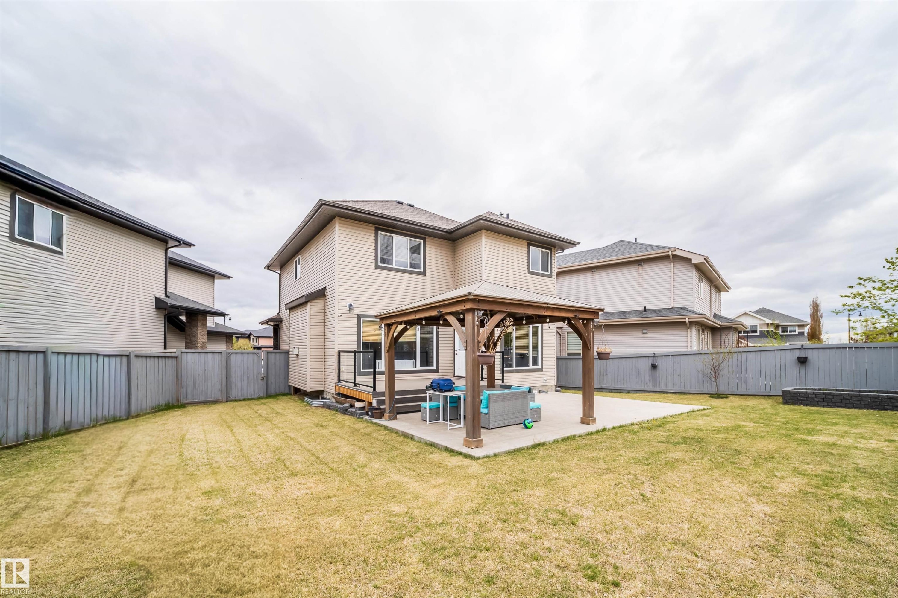 Expansive backyard featuring a concrete patio with an attached wooden gazebo, a composite deck with black metal railings, and a rectangular raised garden bed - 1508 Cunningham Cape Cape, Edmonton, AB - Outdoor With Exterior