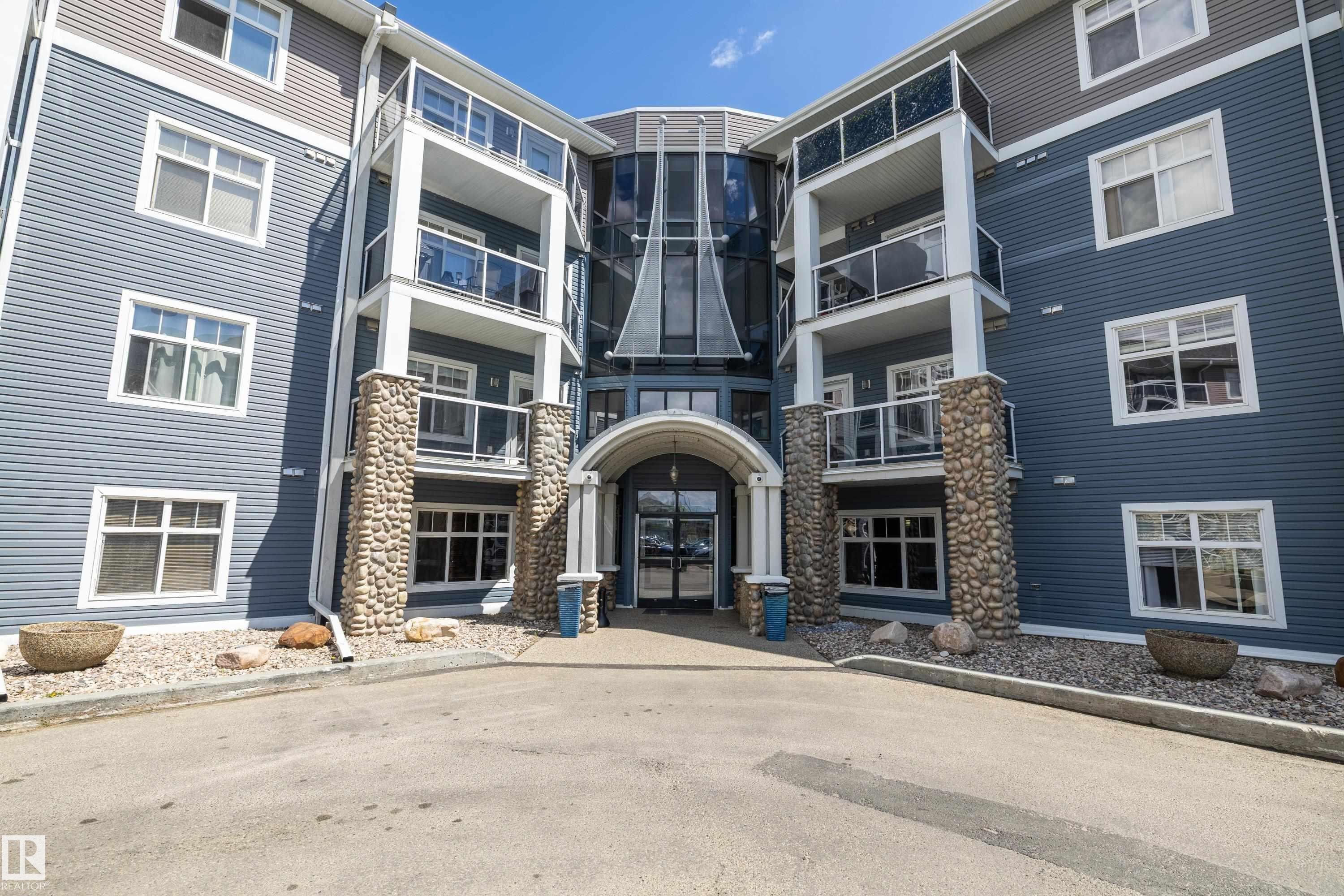 Multi-story building with blue siding and stone facade accents - 406 16035 132 Street, Edmonton, AB - Outdoor With Balcony With Facade