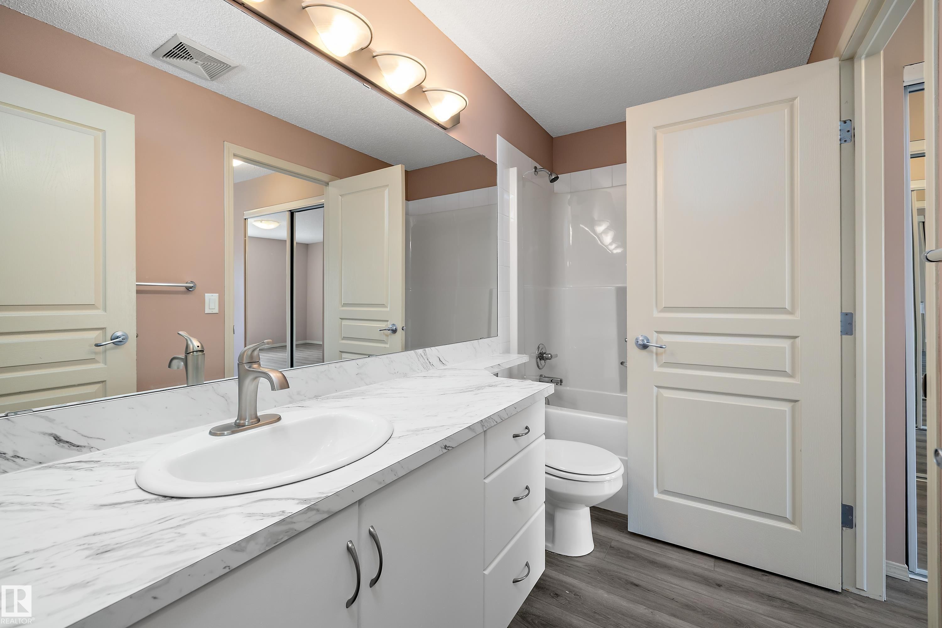 Bathroom featuring a white vanity with a patterned countertop, undermount sink, and brushed nickel faucet - 406 16035 132 Street, Edmonton, AB - Indoor Photo Showing Bathroom