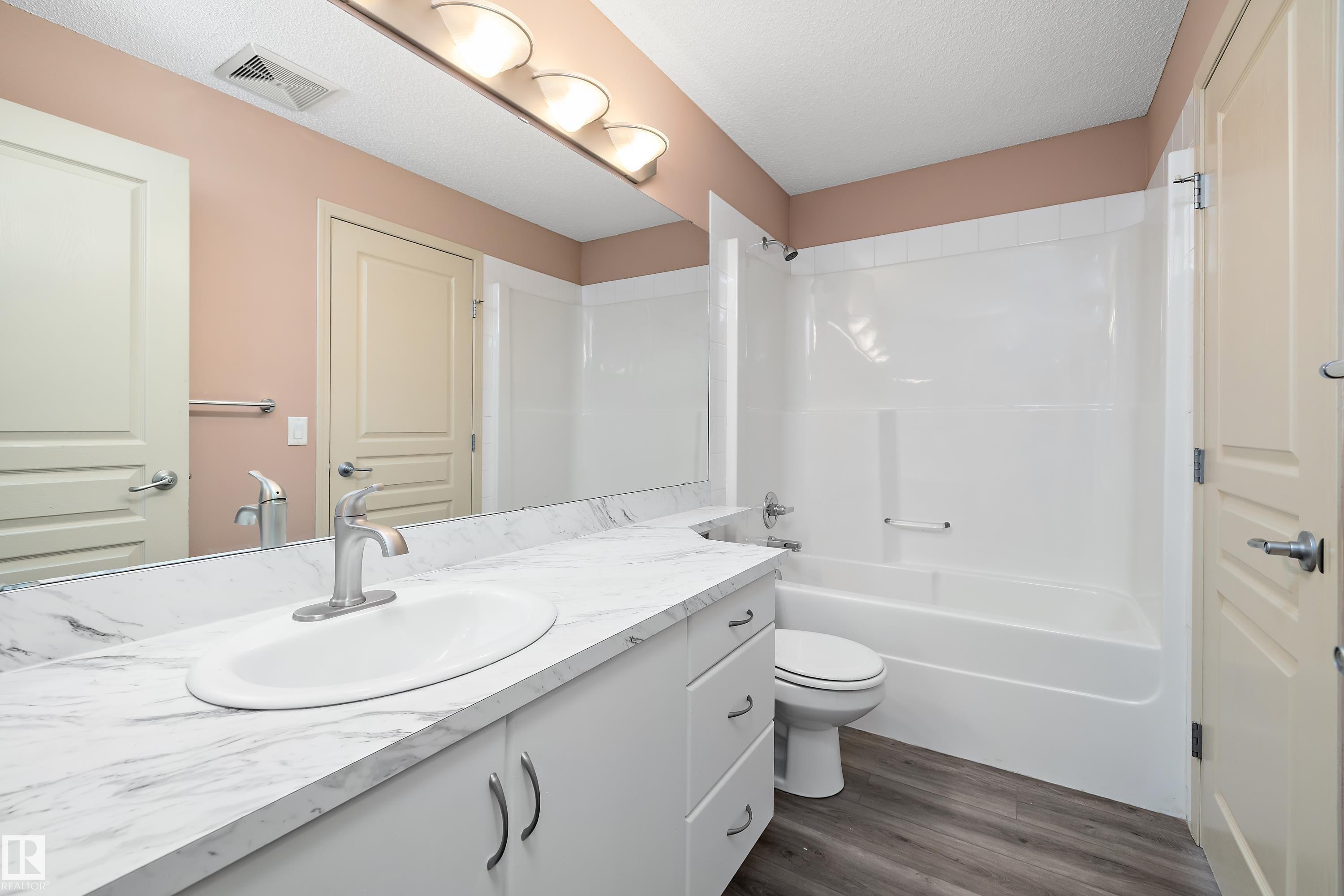Bathroom vanity with a white countertop and integrated sink, complete with a chrome faucet - 406 16035 132 Street, Edmonton, AB - Indoor Photo Showing Bathroom