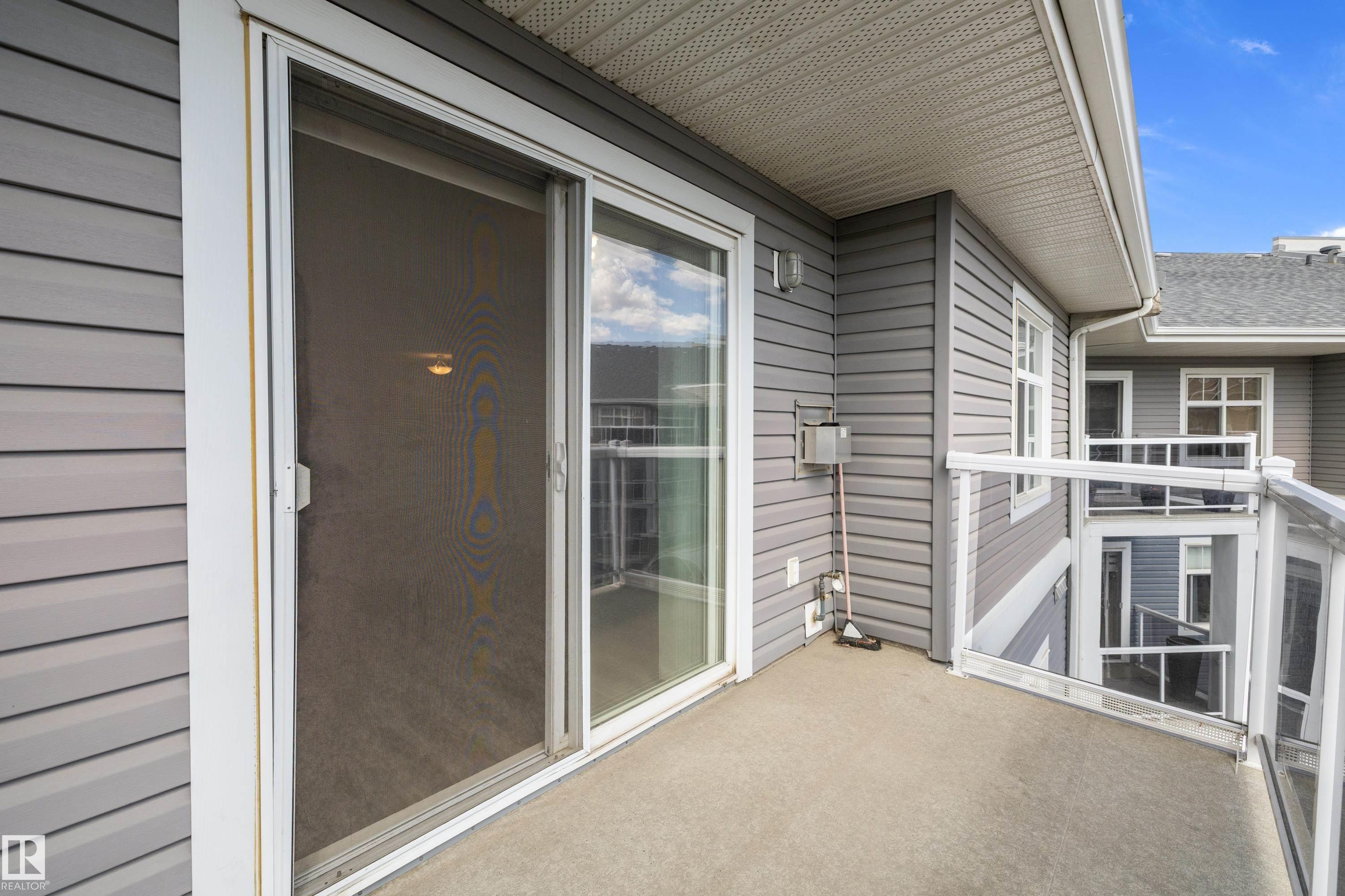 Private balcony with concrete flooring, glass panel railing, and grey siding - 406 16035 132 Street, Edmonton, AB - Outdoor With Balcony With Deck Patio Veranda With Exterior