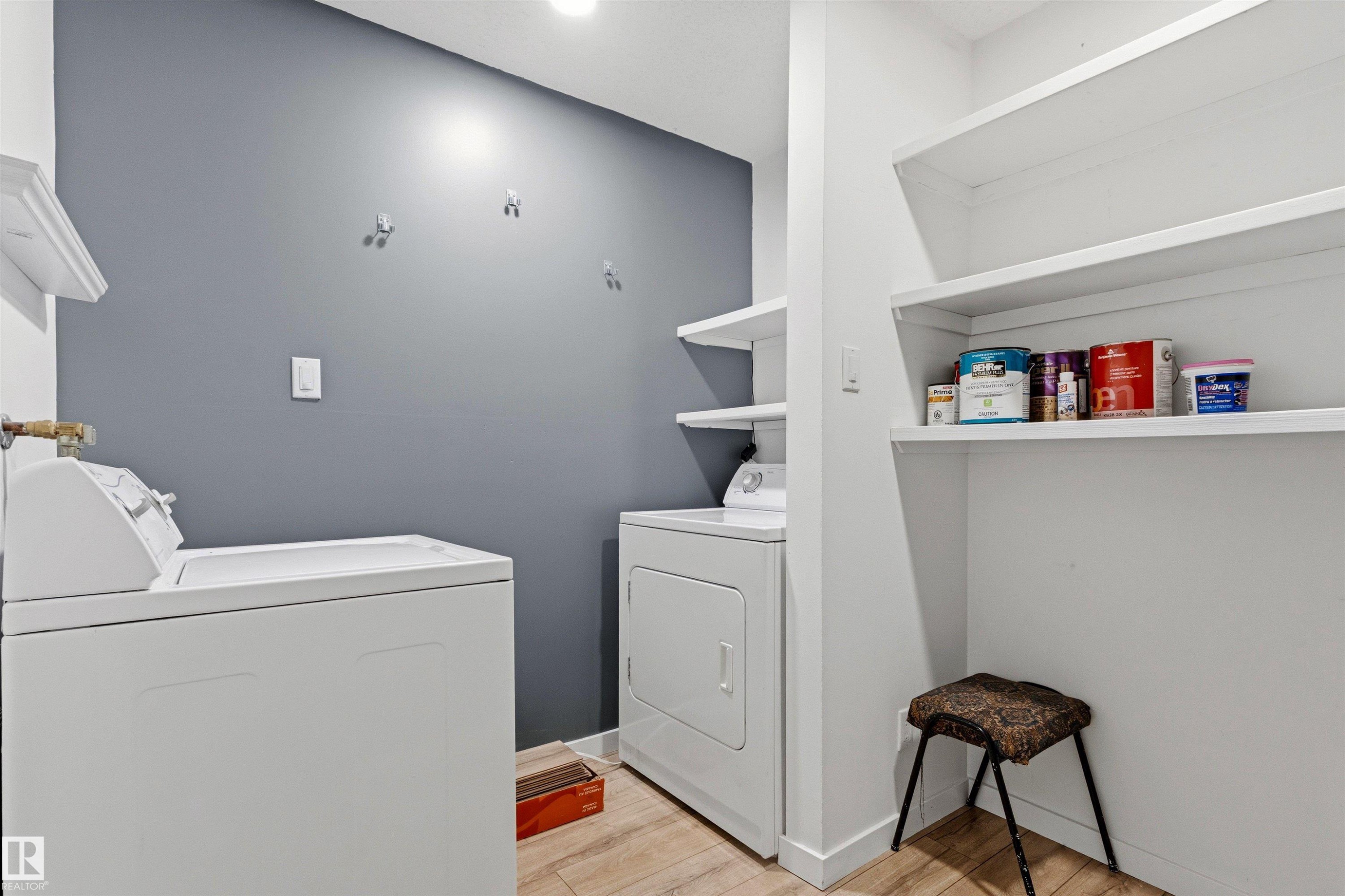 Dedicated laundry area featuring a light wood-finish floor, white trim, and a contrasting gray accent wall - 217 14819 51 Avenue, Edmonton, AB