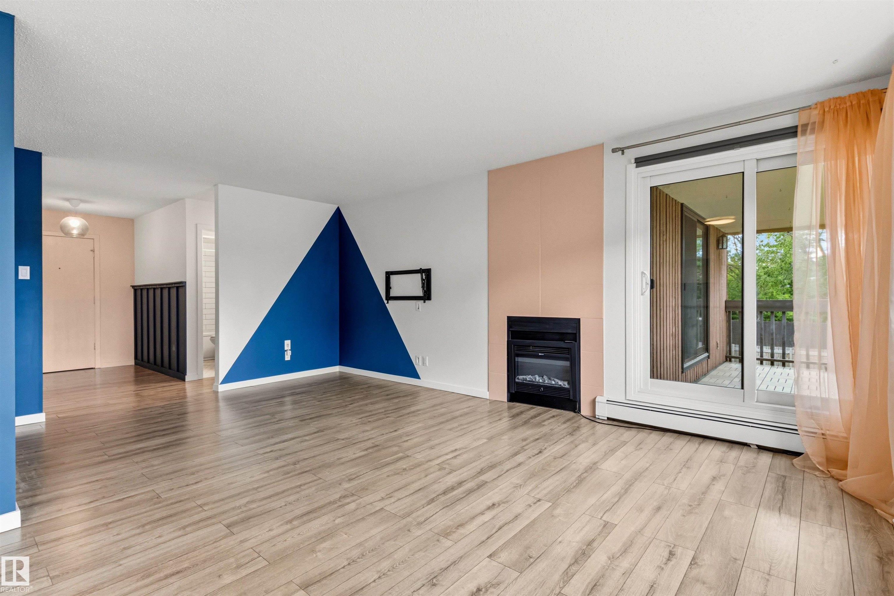 Living area featuring wood-finish flooring, a built-in fireplace, and a sliding glass door - 217 14819 51 Avenue, Edmonton, AB