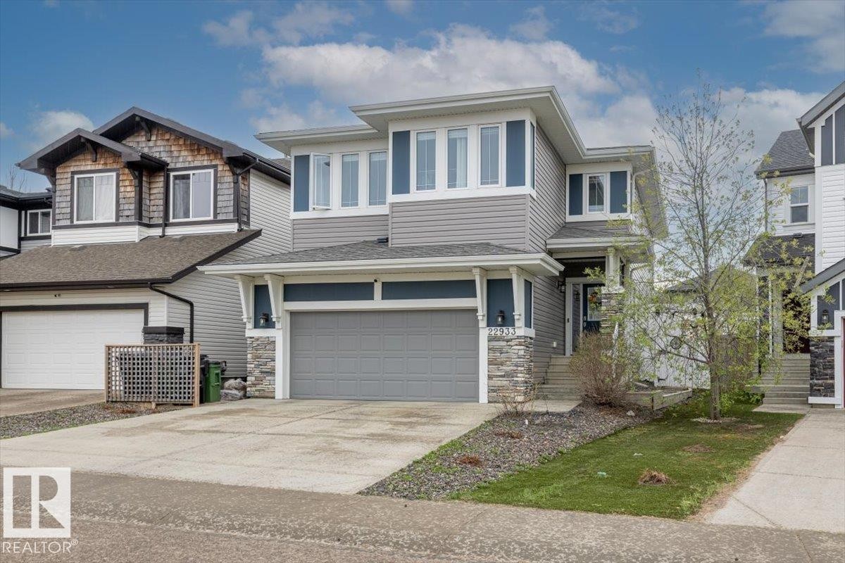 Contemporary two-story exterior featuring gray horizontal siding, blue vertical accents, and stone veneer detailing - 22933 94A Avenue, Edmonton, AB - Outdoor With Facade