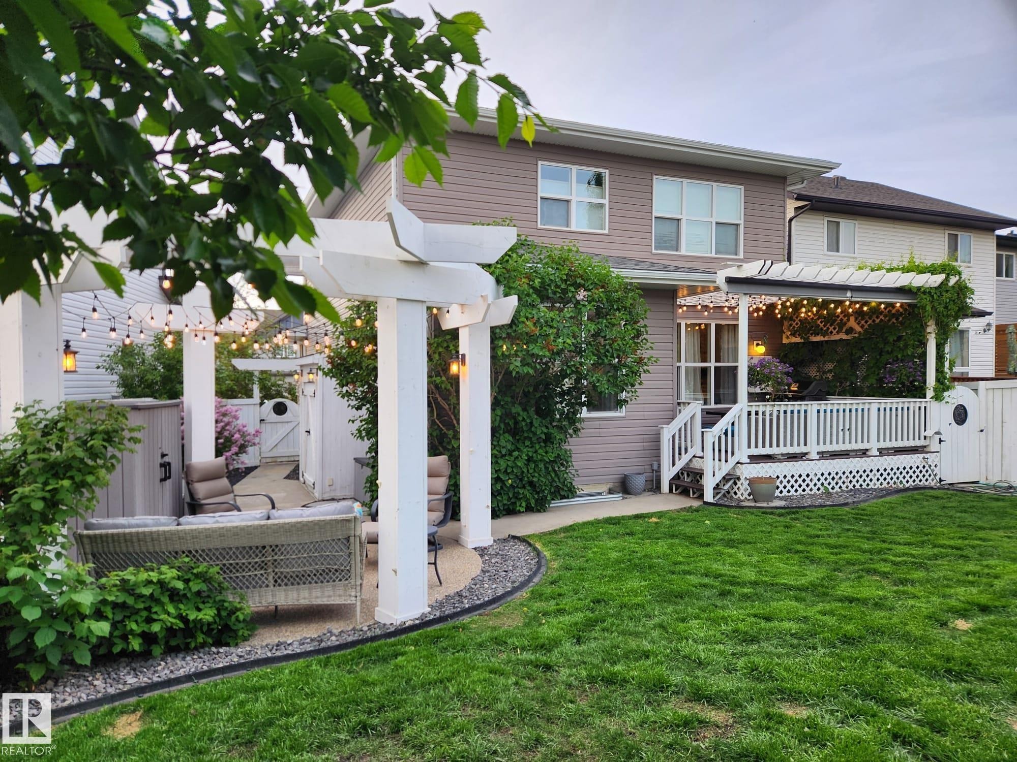 Expansive backyard featuring a manicured lawn, a gravel patio with pergola, and a raised deck with a second pergola - 22933 94A Avenue, Edmonton, AB - Outdoor With Deck Patio Veranda With Exterior