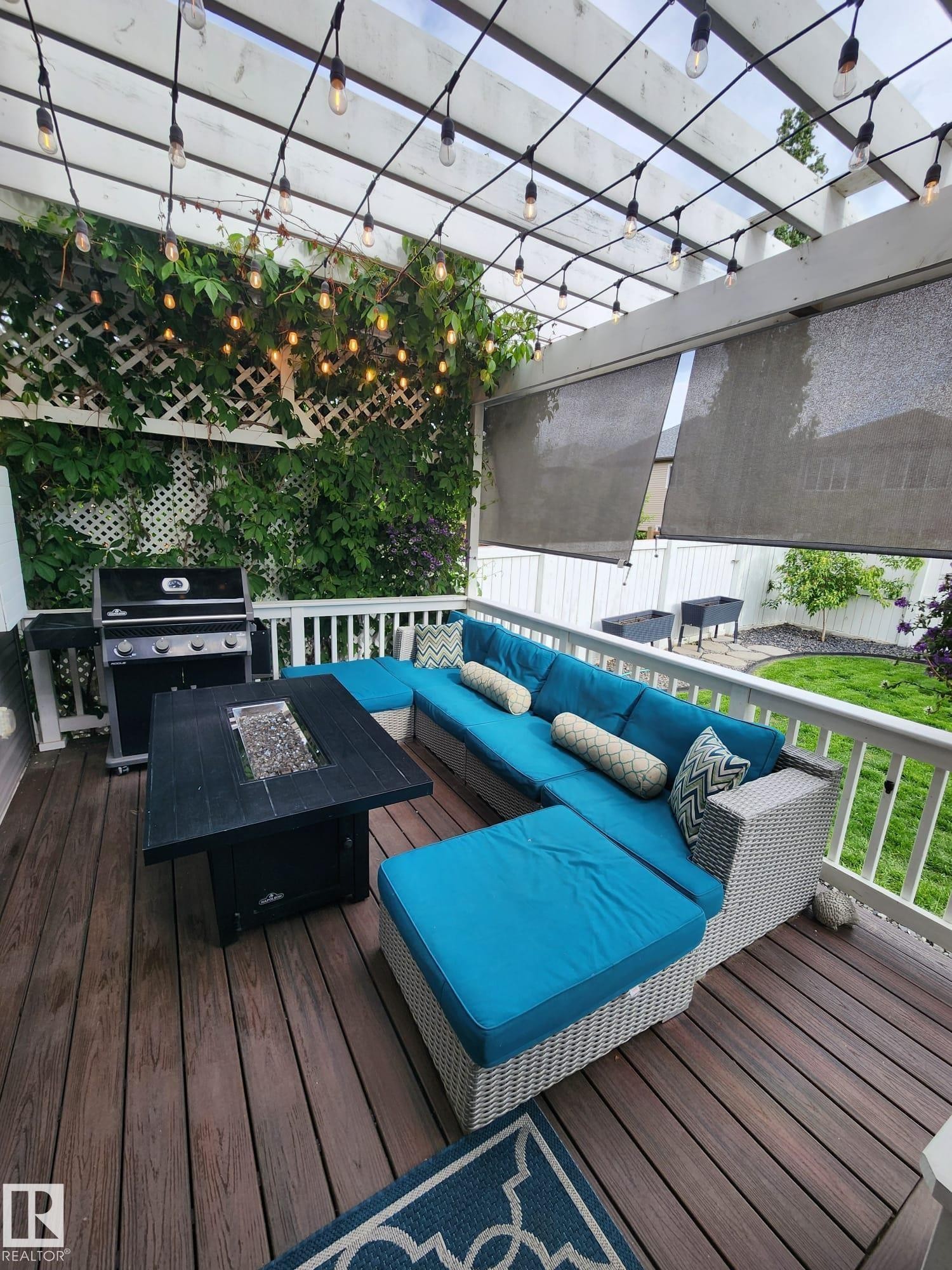 Expansive deck featuring wood-finish flooring, a white pergola with strung lighting, and a lattice privacy wall with climbing greenery - 22933 94A Avenue, Edmonton, AB - Outdoor With View