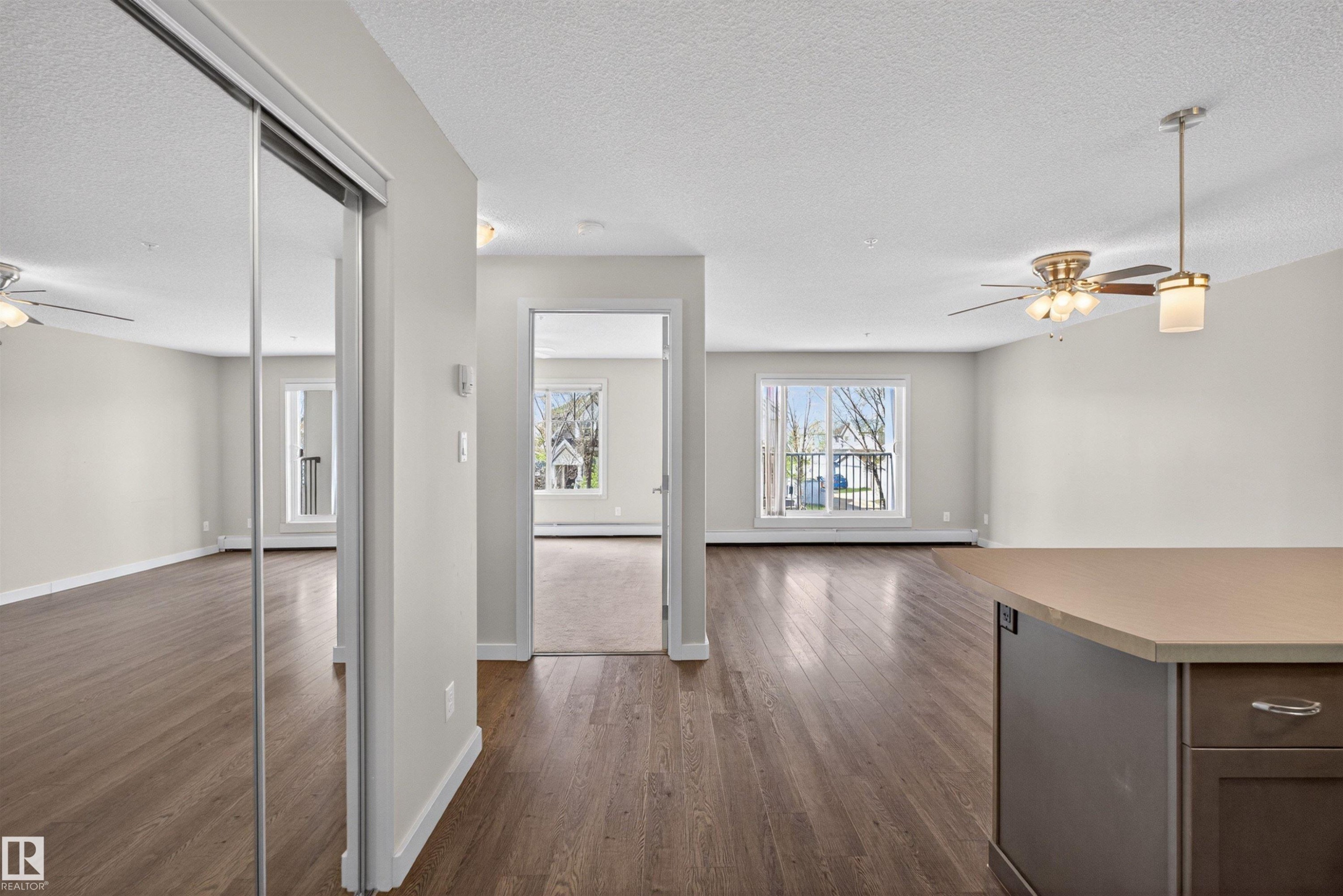 Open-concept living space featuring wood-finish flooring, light gray walls, and multiple ceiling fans - 215 6084 Stanton Drive, Edmonton, AB - Indoor Photo Showing Other Room