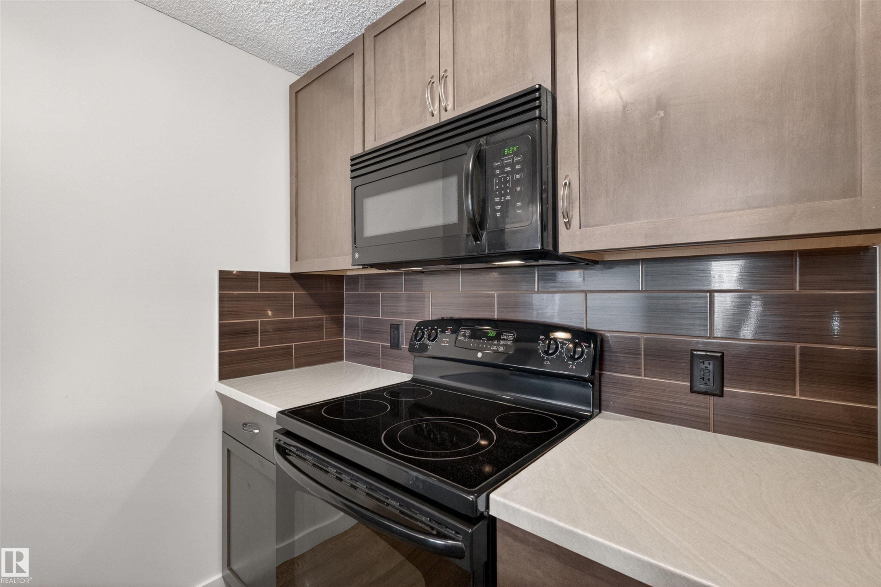 Modern kitchen featuring light gray cabinetry, an over-the-range microwave, and a black electric range - 215 6084 Stanton Drive, Edmonton, AB - Indoor Photo Showing Kitchen