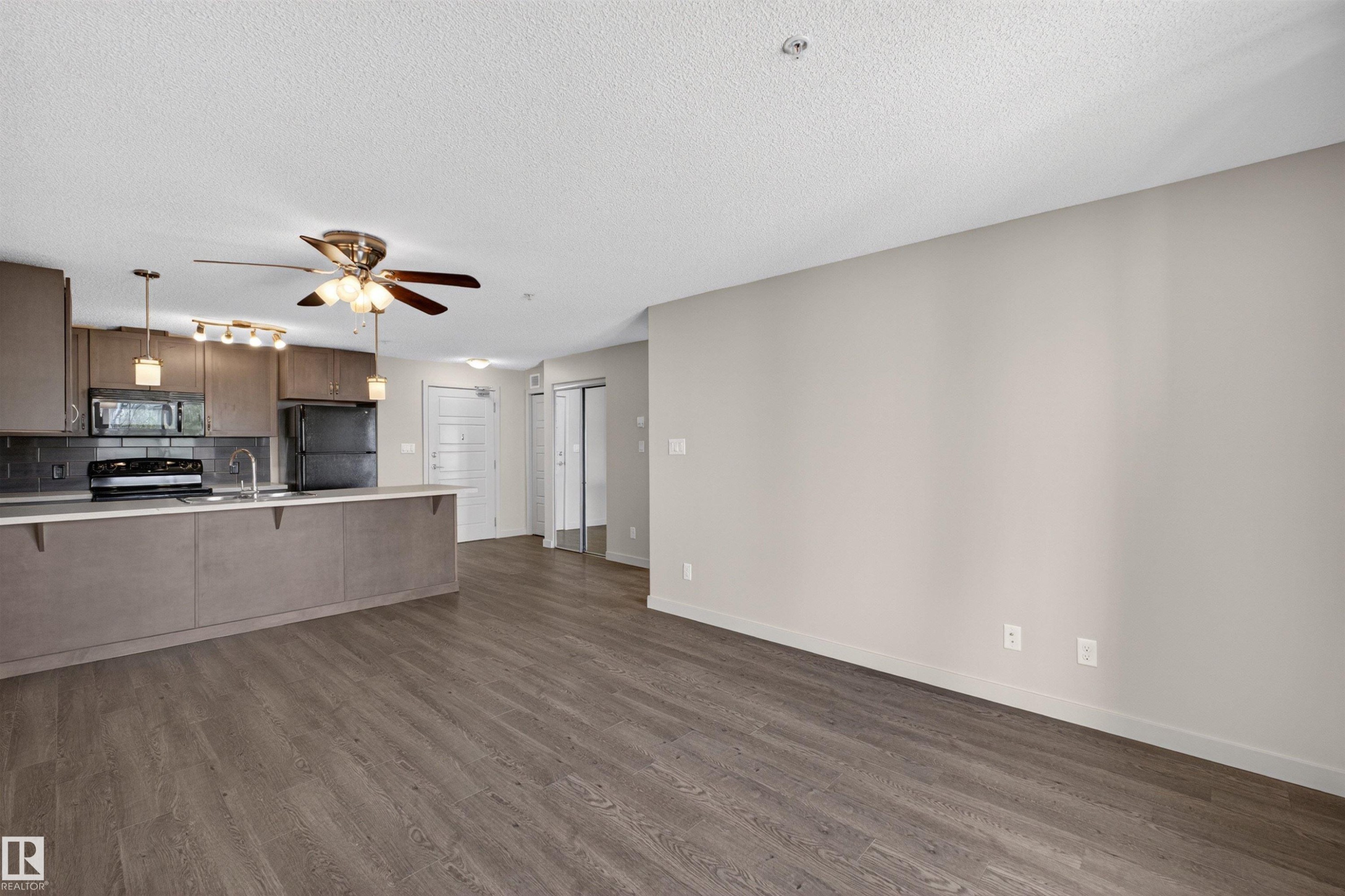 Open-concept living area with wood-finish flooring extending into the kitchen - 215 6084 Stanton Drive, Edmonton, AB - Indoor Photo Showing Kitchen
