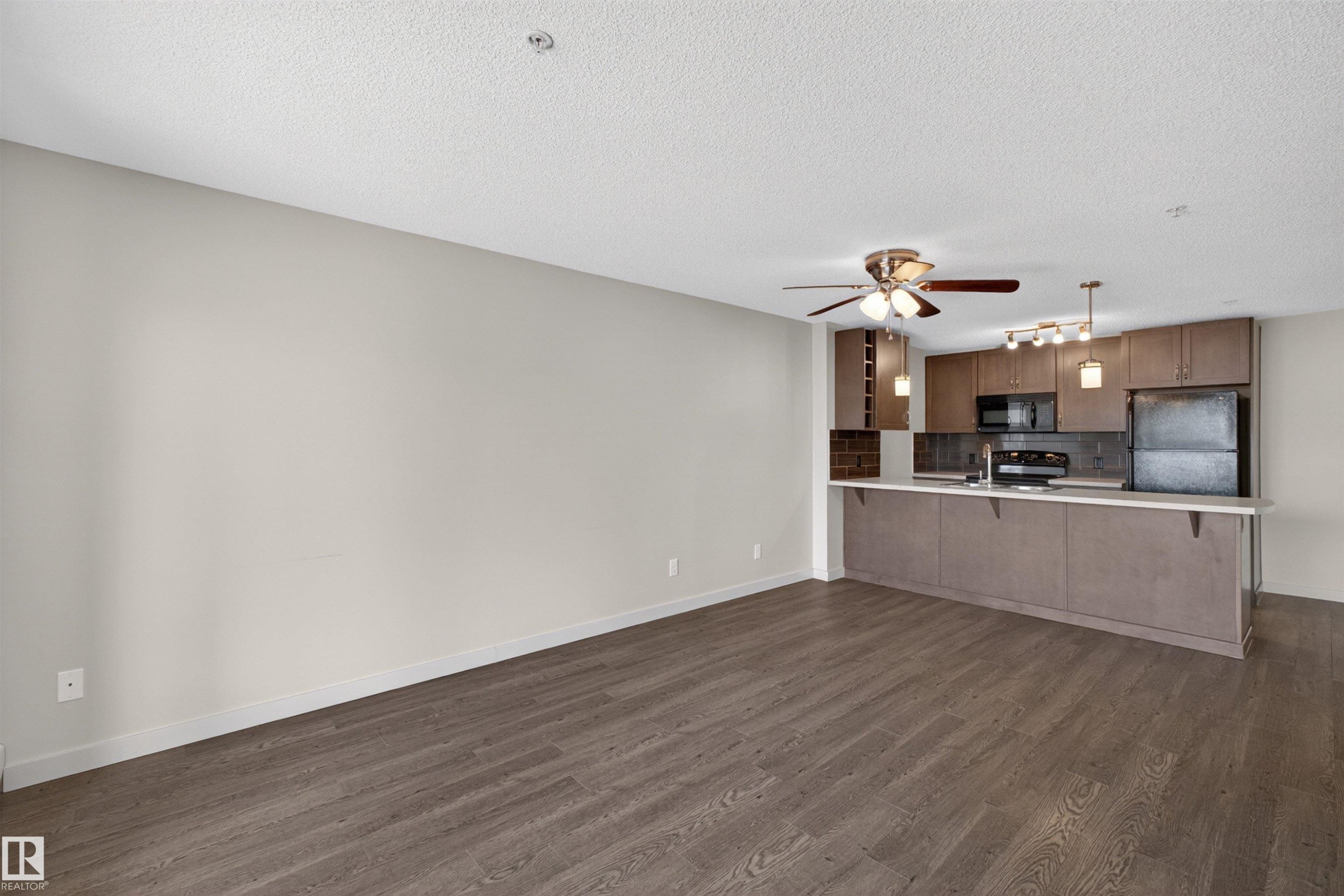 Open-concept living area featuring wood-finish flooring, a contemporary ceiling fan, and recessed lighting - 215 6084 Stanton Drive, Edmonton, AB - Indoor Photo Showing Kitchen