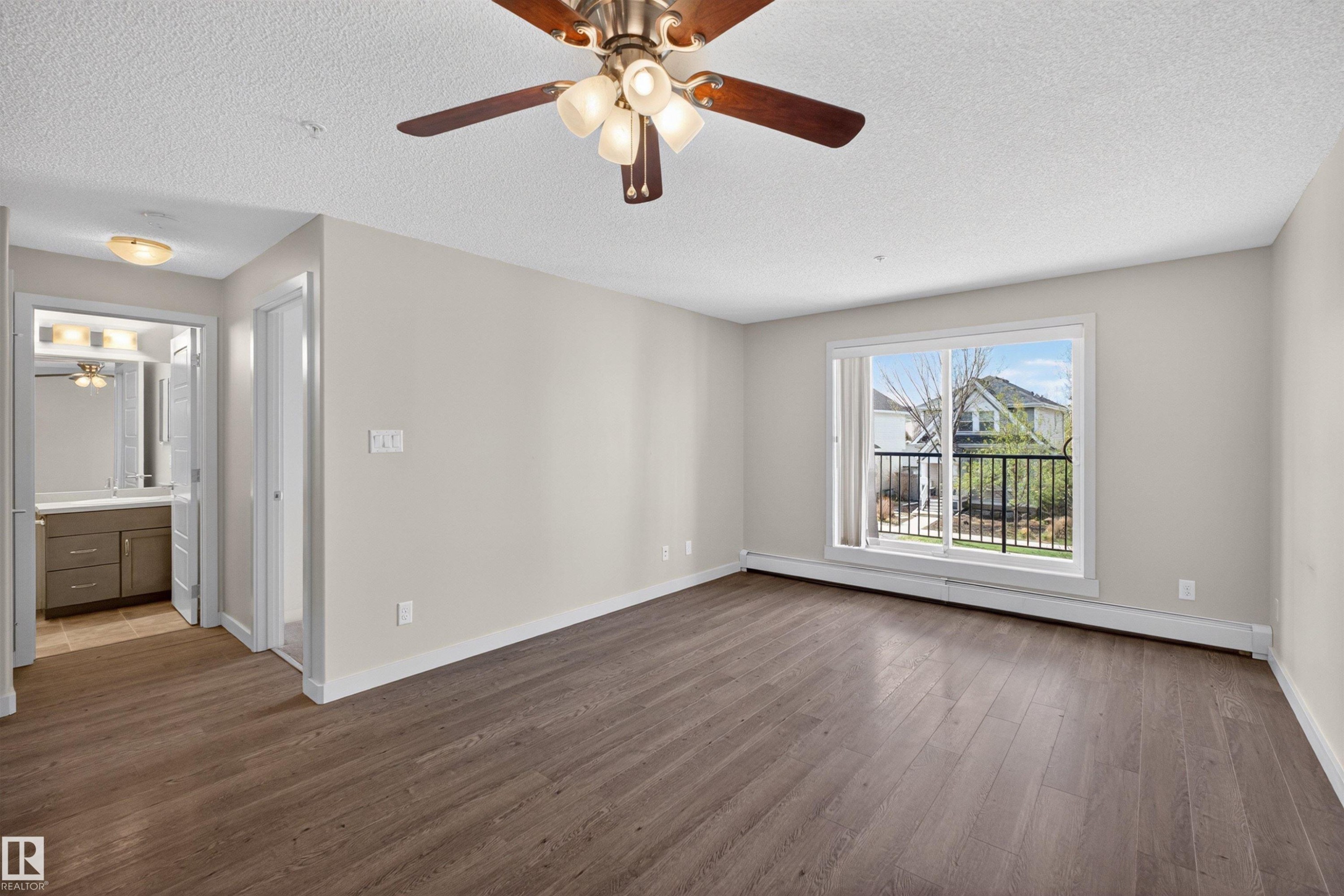 Spacious room featuring wood-finish flooring, a ceiling fan with integrated lighting, and neutral wall tones - 215 6084 Stanton Drive, Edmonton, AB - Indoor