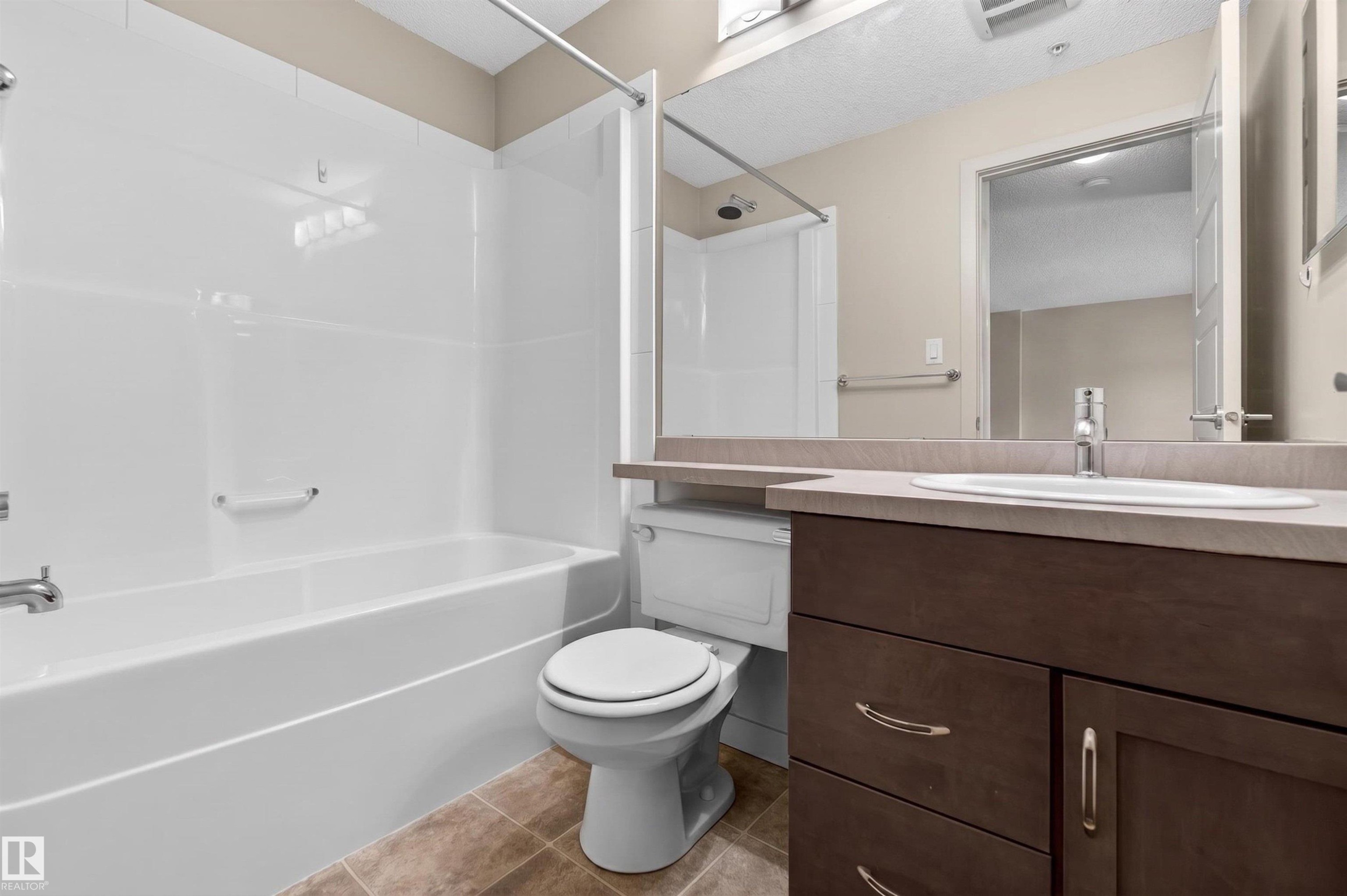Bathroom featuring a white bathtub and shower surround, a toilet, and a vanity with a recessed sink - 215 6084 Stanton Drive, Edmonton, AB - Indoor Photo Showing Bathroom