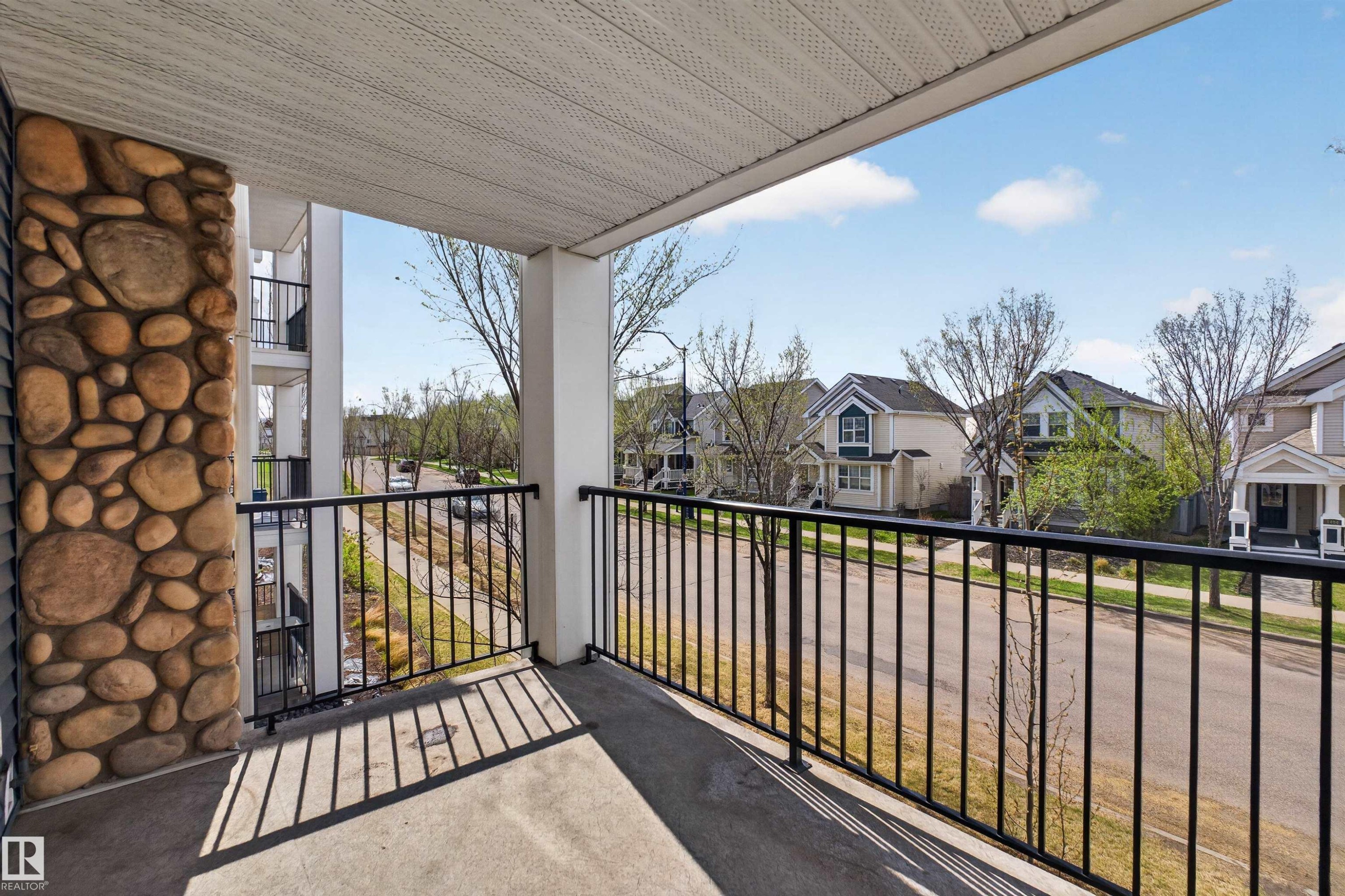 Balcony space featuring a concrete floor, stone column, and black metal railing - 215 6084 Stanton Drive, Edmonton, AB - Outdoor With Balcony With Exterior