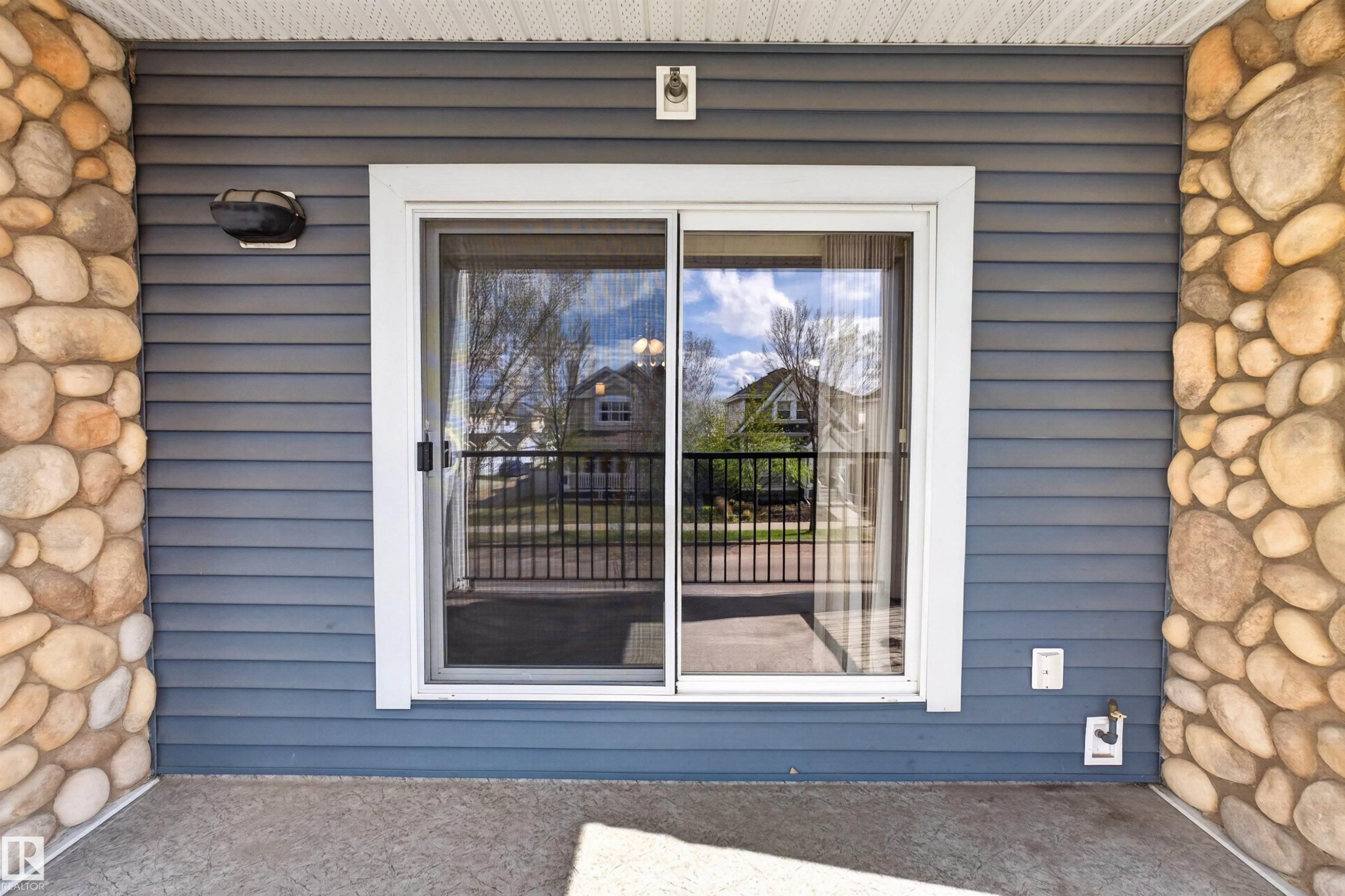 Sliding glass door with white frame, set within blue horizontal siding - 215 6084 Stanton Drive, Edmonton, AB - Outdoor With Exterior