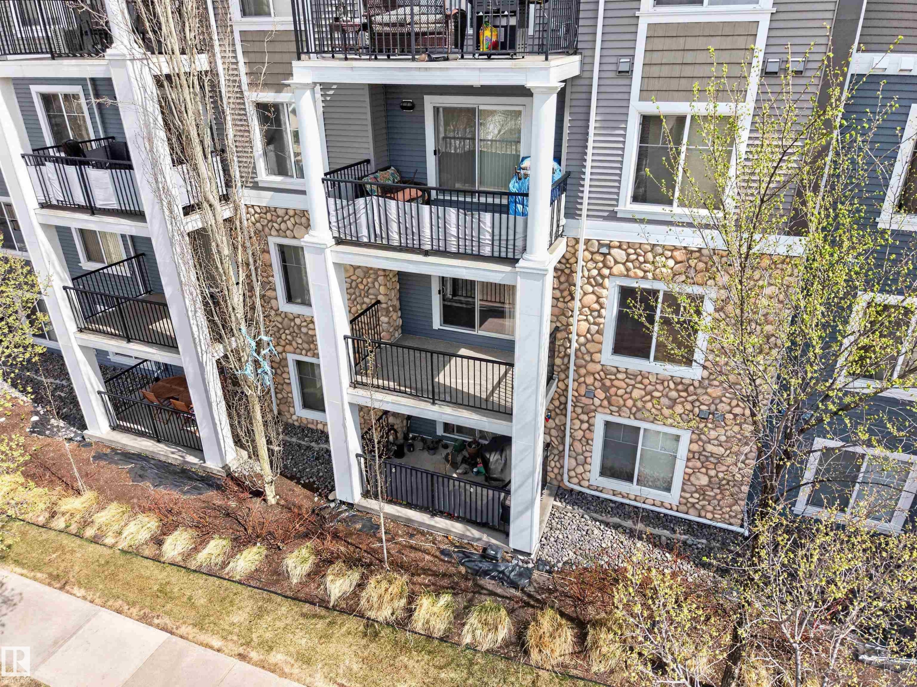 Multi-story residential building featuring balconies with black metal railings and white support columns - 215 6084 Stanton Drive, Edmonton, AB - Outdoor With Balcony