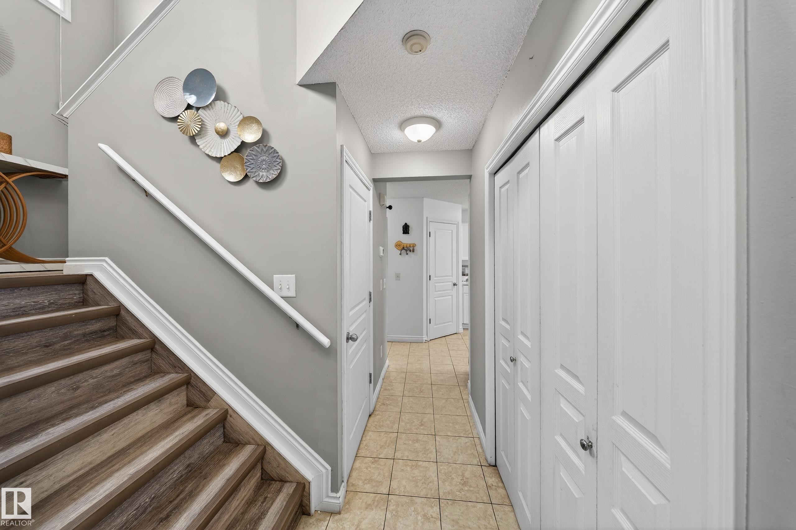 Hallway featuring a staircase with wood-style treads, a textured ceiling, and tiled flooring - 3517 25 Street, Edmonton, AB - Indoor Photo Showing Other Room