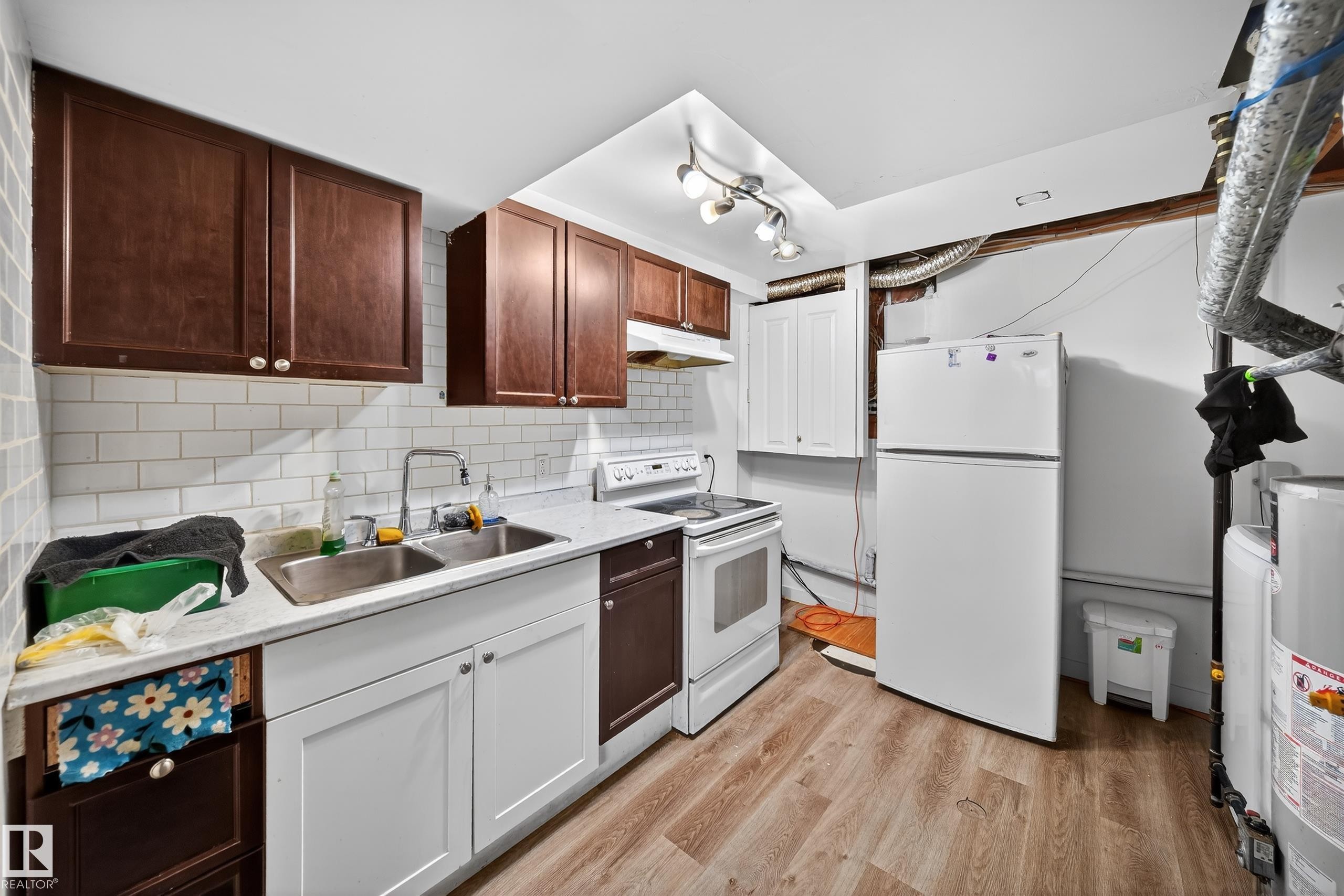 The property includes a kitchen area featuring warm wood upper cabinetry, a white subway tile backsplash, and a double basin stainless steel sink - 3517 25 Street, Edmonton, AB - Indoor Photo Showing Kitchen With Double Sink