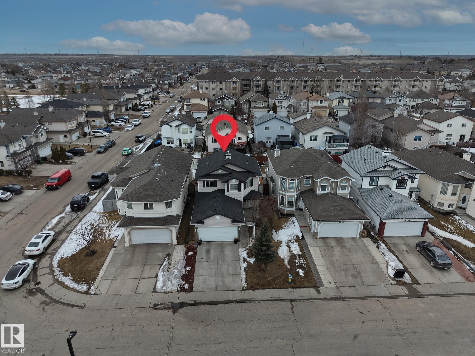 This property features a prominent residential structure with a dark roof and light-colored siding, complemented by an attached garage with a concrete driveway - 3517 25 Street, Edmonton, AB - Outdoor