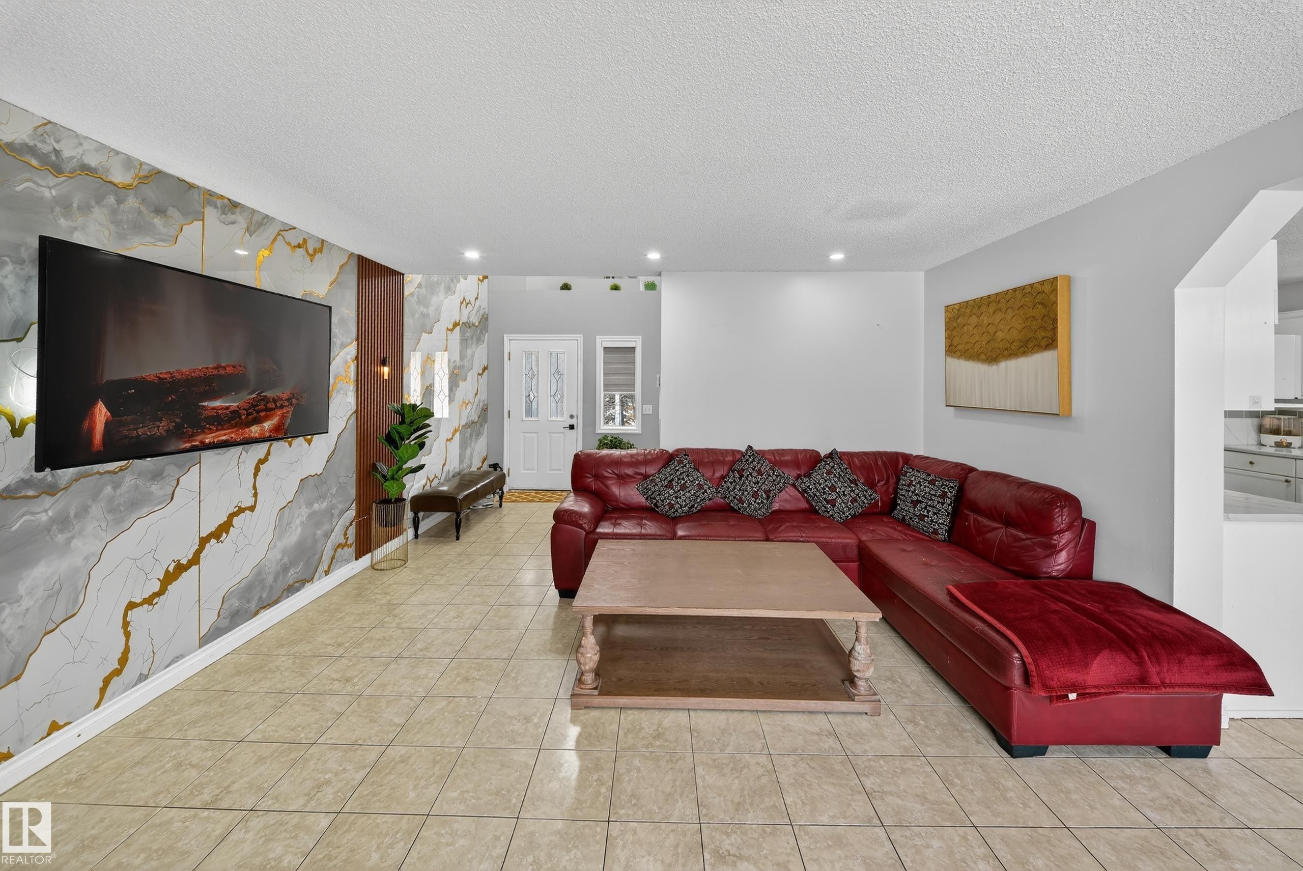 The living area features tiled flooring, recessed lighting, and a decorative wall with a mounted television - 3517 25 Street, Edmonton, AB - Indoor Photo Showing Living Room