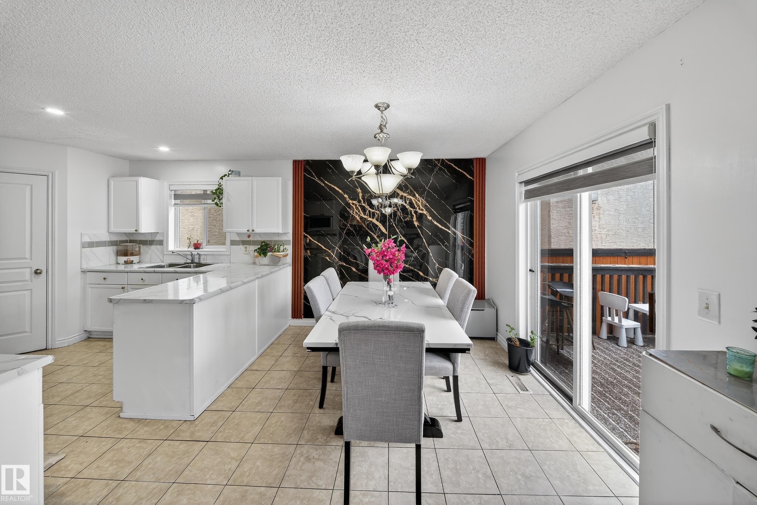 The kitchen and dining area feature white cabinetry, a large kitchen island with a white countertop, and tiled flooring - 3517 25 Street, Edmonton, AB - Indoor