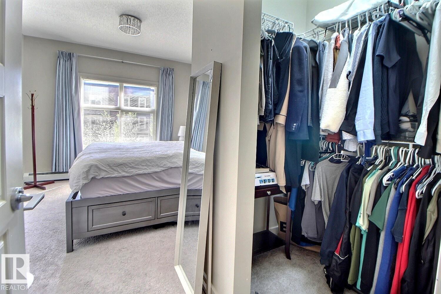 Bedroom featuring a window with light blue drapes, light-colored carpeting, and a ceiling-mounted light fixture - 327 508 Griesbach Parade, Edmonton, AB - Indoor With Storage