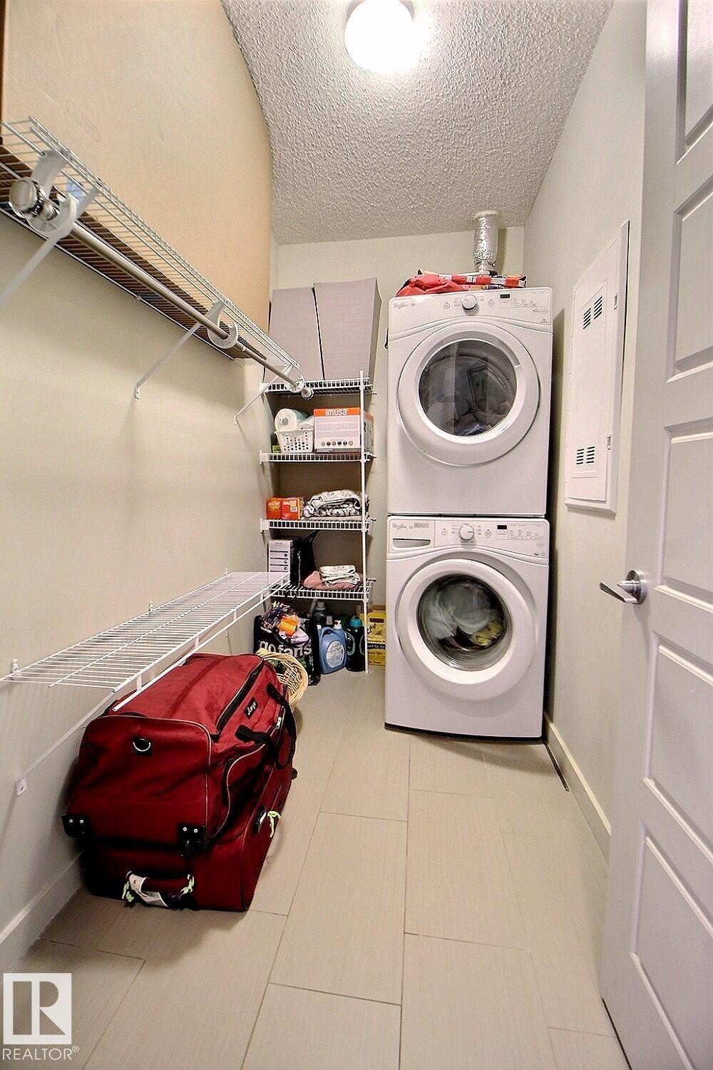 Dedicated laundry area featuring stacked appliances - 327 508 Griesbach Parade, Edmonton, AB - Indoor Photo Showing Laundry Room