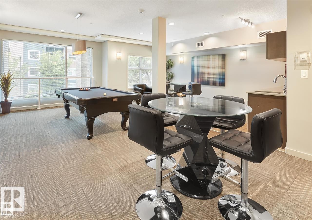Open-concept amenity space featuring patterned carpet flooring and a generously sized window wall - 327 508 Griesbach Parade, Edmonton, AB - Indoor Photo Showing Other Room