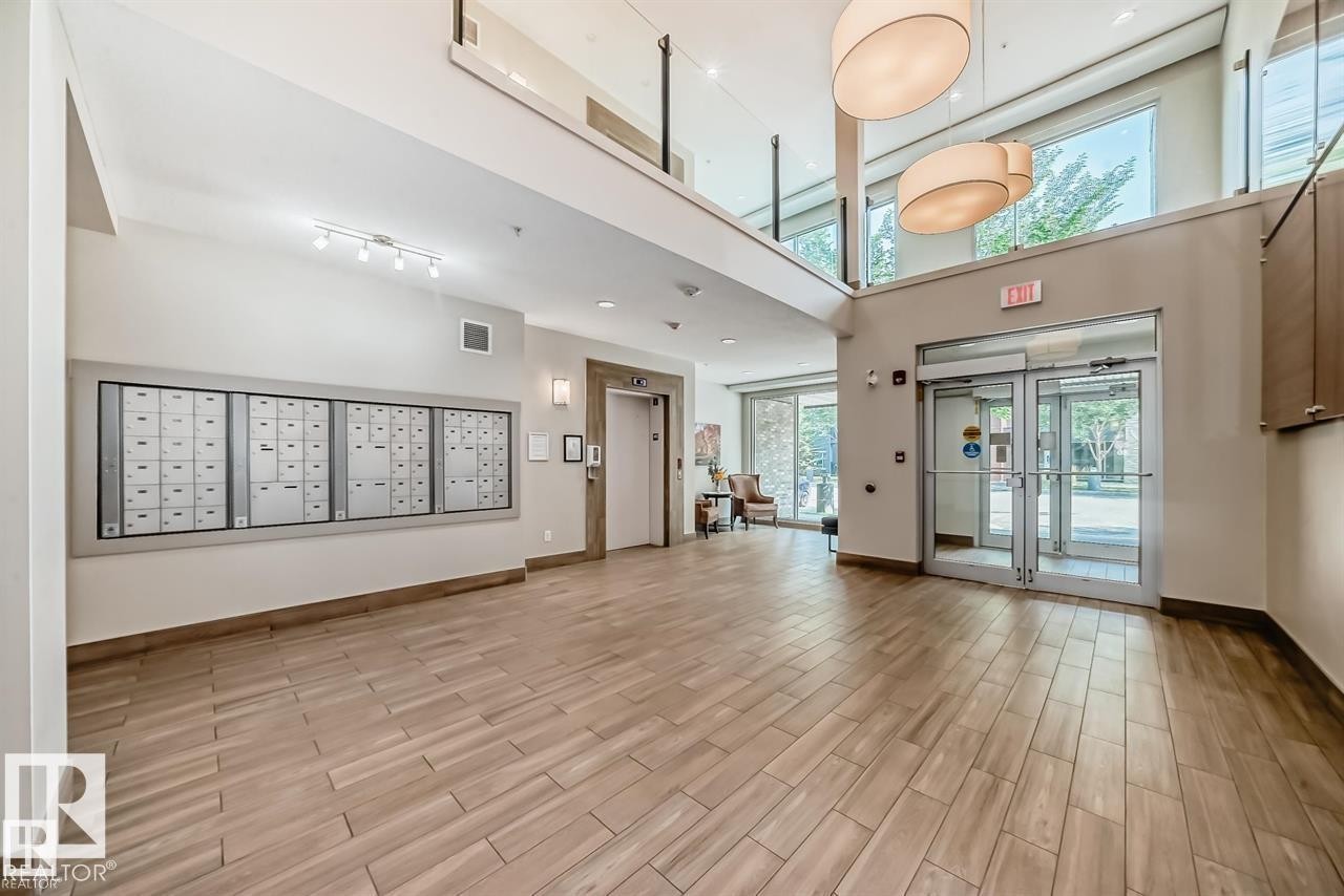 Spacious lobby featuring wood-finish tile flooring, a secure mailbox bank, and a modern elevator - 327 508 Griesbach Parade, Edmonton, AB - Indoor Photo Showing Other Room