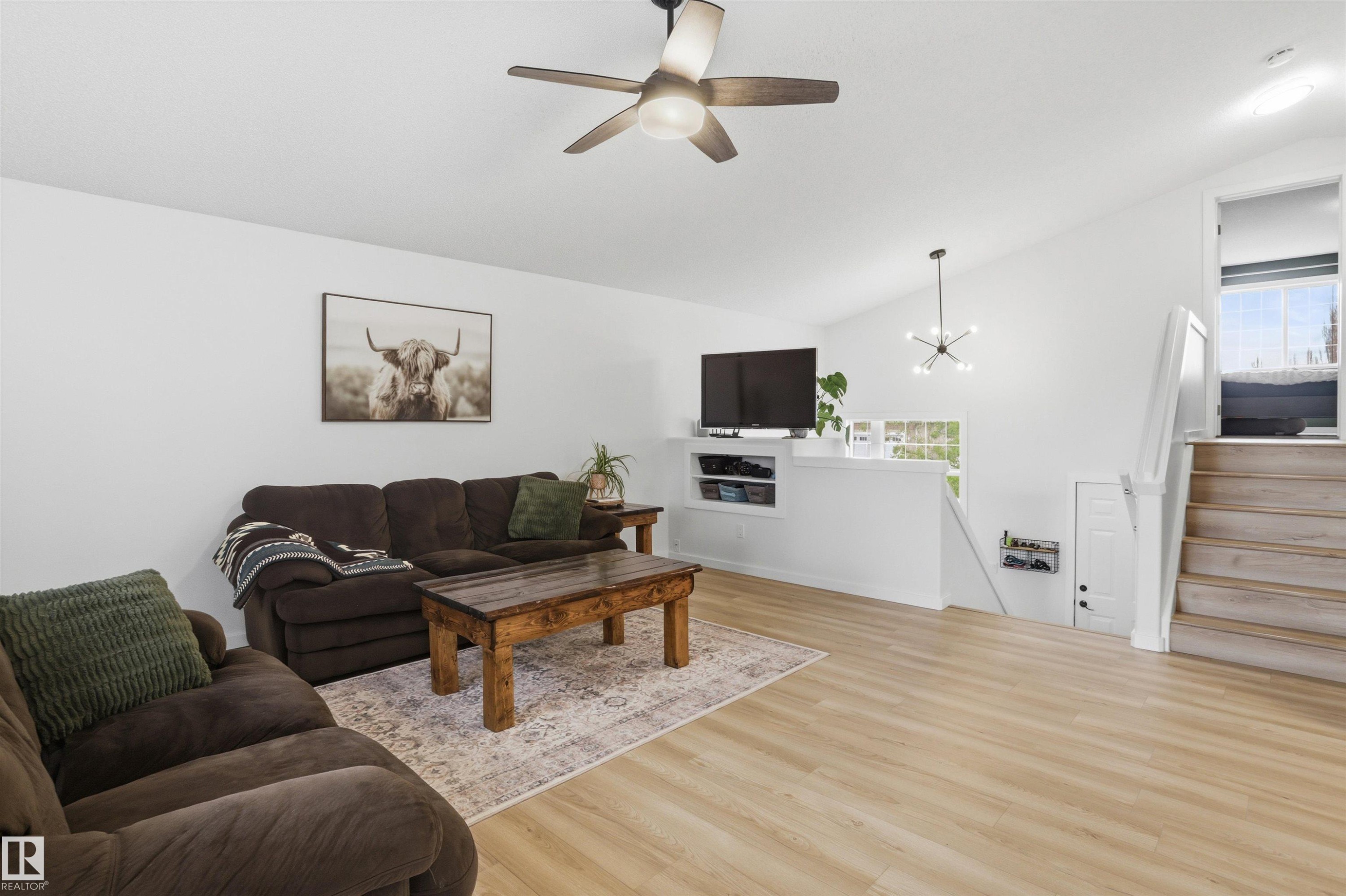 Spacious living area featuring a vaulted ceiling, wood-finish flooring, and a modern ceiling fan - 396 Kananaskis Way, Devon, AB - Indoor Photo Showing Living Room