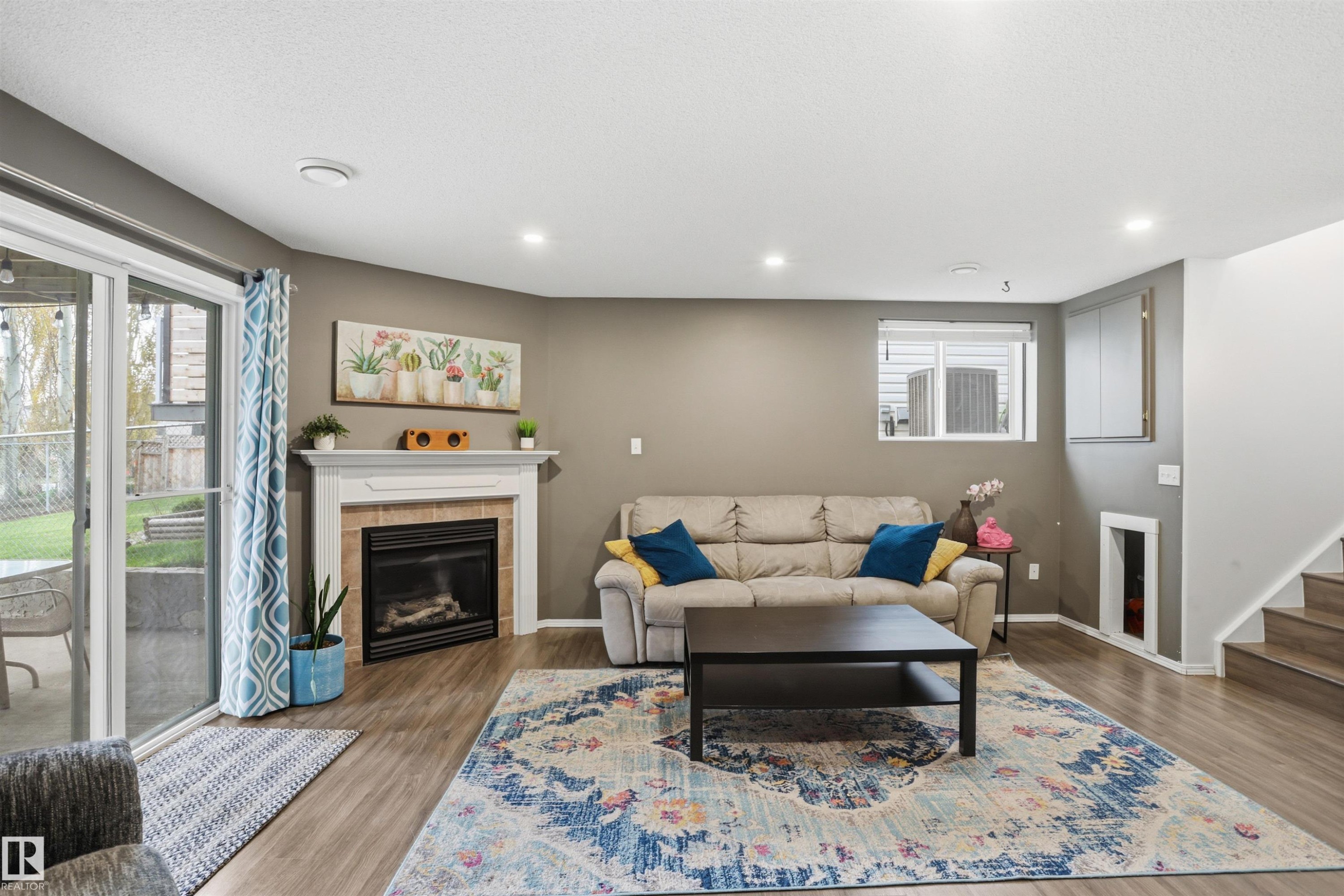 Inviting living area featuring wood-finish flooring and recessed lighting - 396 Kananaskis Way, Devon, AB - Indoor With Fireplace