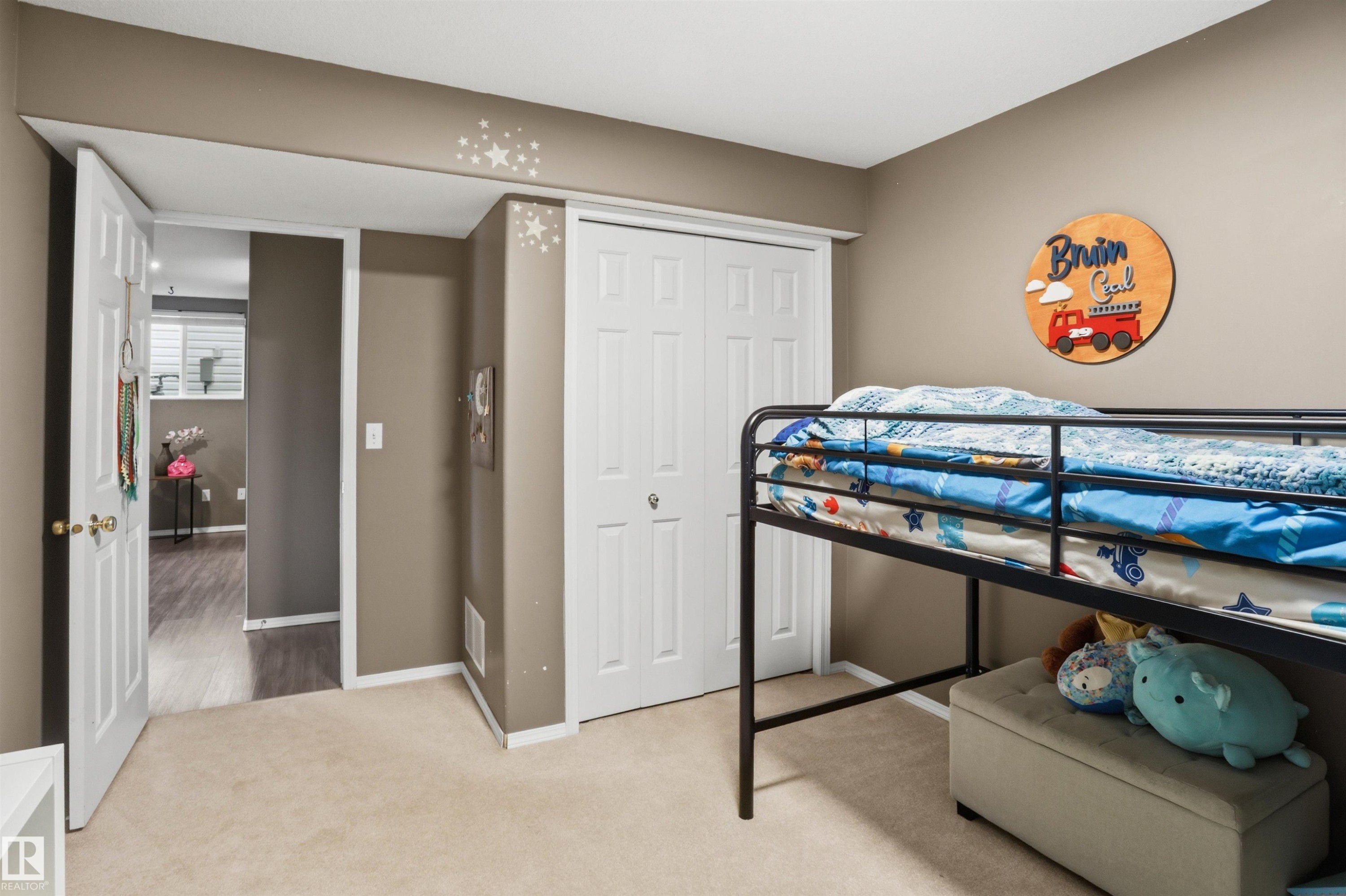 Carpeted room featuring a white bi-fold closet door, neutral wall paint, and white trim - 396 Kananaskis Way, Devon, AB - Indoor Photo Showing Bedroom