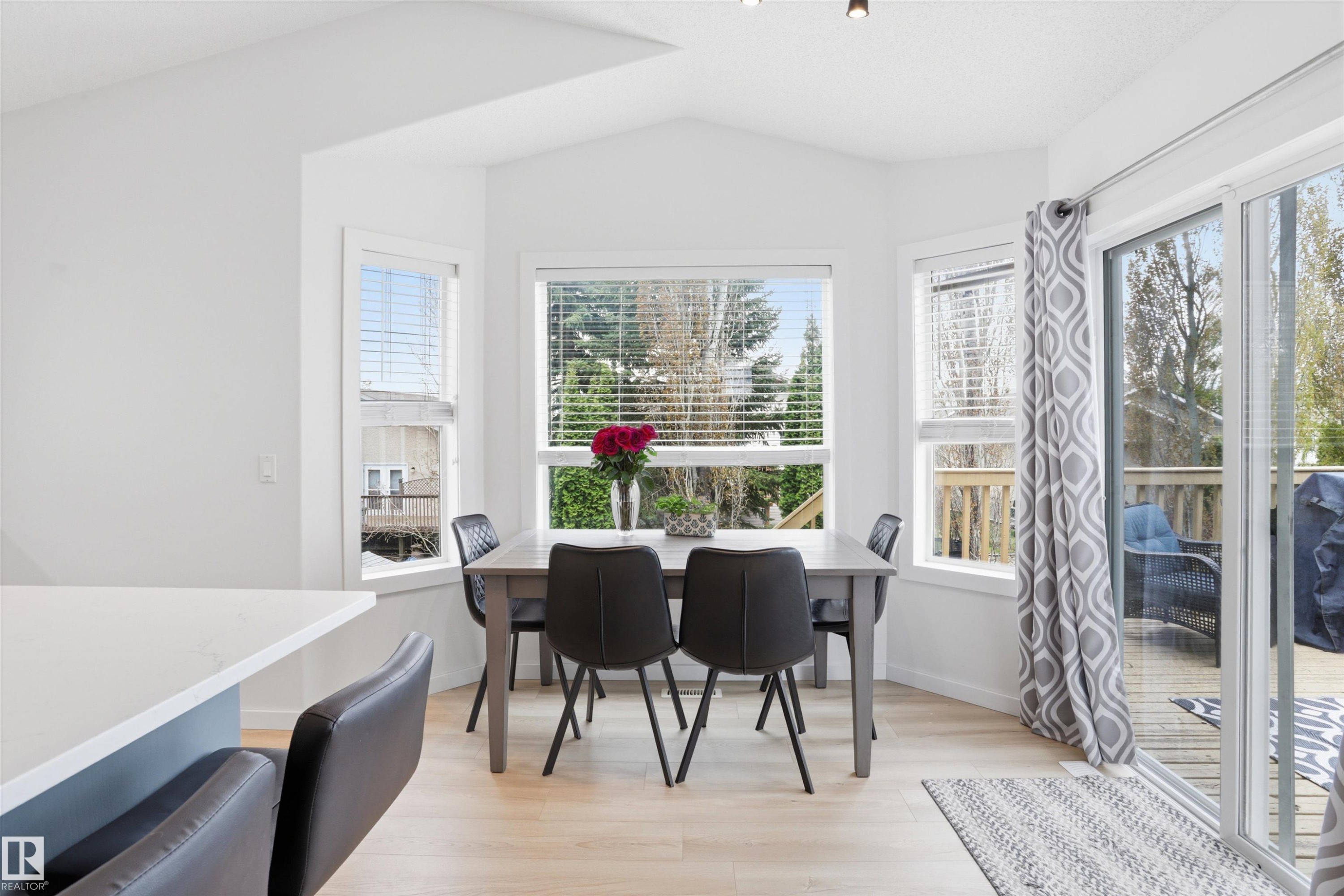 Dining area featuring multiple windows with blinds, a sliding glass door to an outdoor deck, light wood-finish flooring, and white painted walls - 396 Kananaskis Way, Devon, AB - Indoor