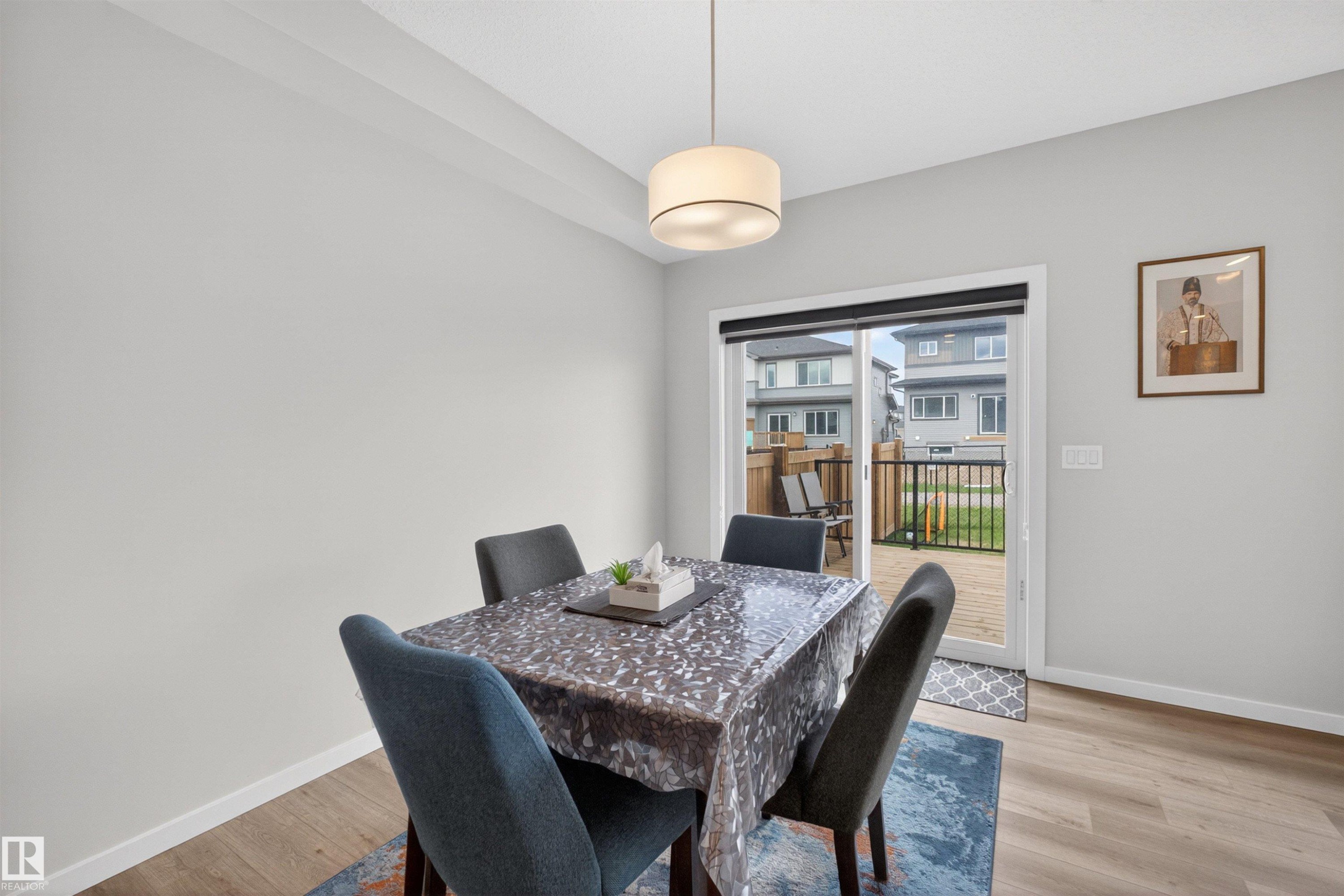 Dining area with wood-finish flooring, light grey walls, and a contemporary drum pendant light - 332 Juniper Cove, Leduc, AB - Indoor Photo Showing Dining Room