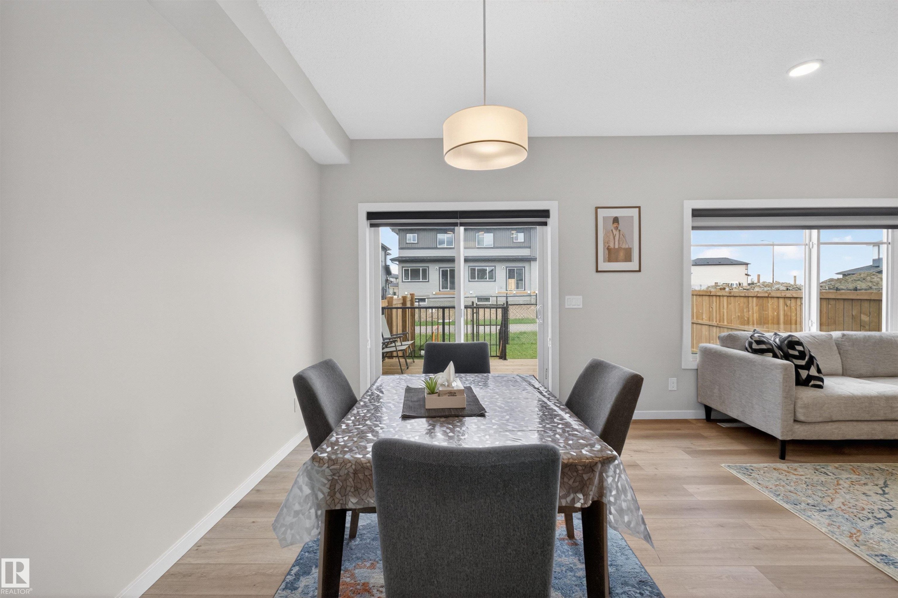 Dining area featuring light wood-finish flooring, a contemporary drum pendant light fixture, and neutral wall tones - 332 Juniper Cove, Leduc, AB - Indoor Photo Showing Dining Room
