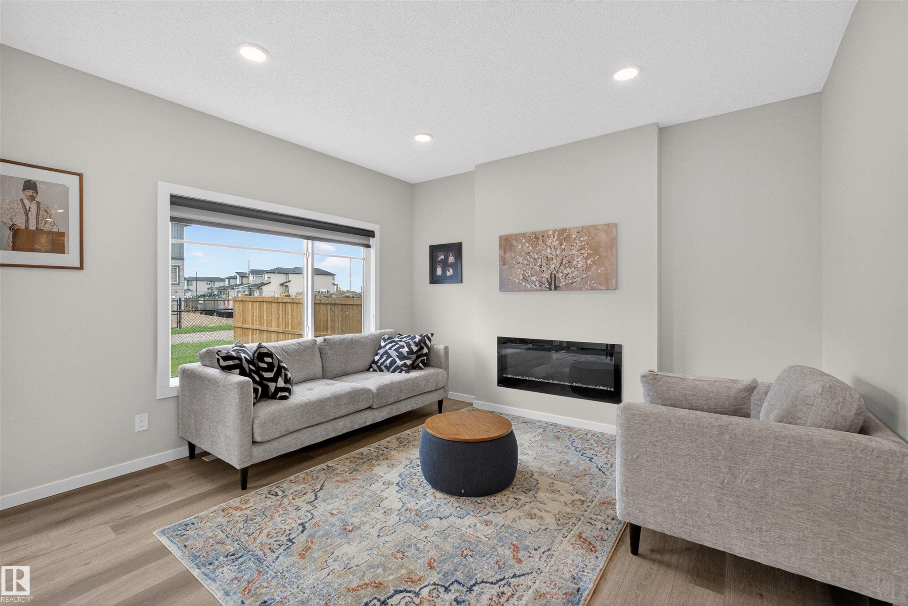 Living area featuring a modern wall-mounted fireplace, a large picture window, and recessed ceiling lighting - 332 Juniper Cove, Leduc, AB - Indoor Photo Showing Living Room With Fireplace