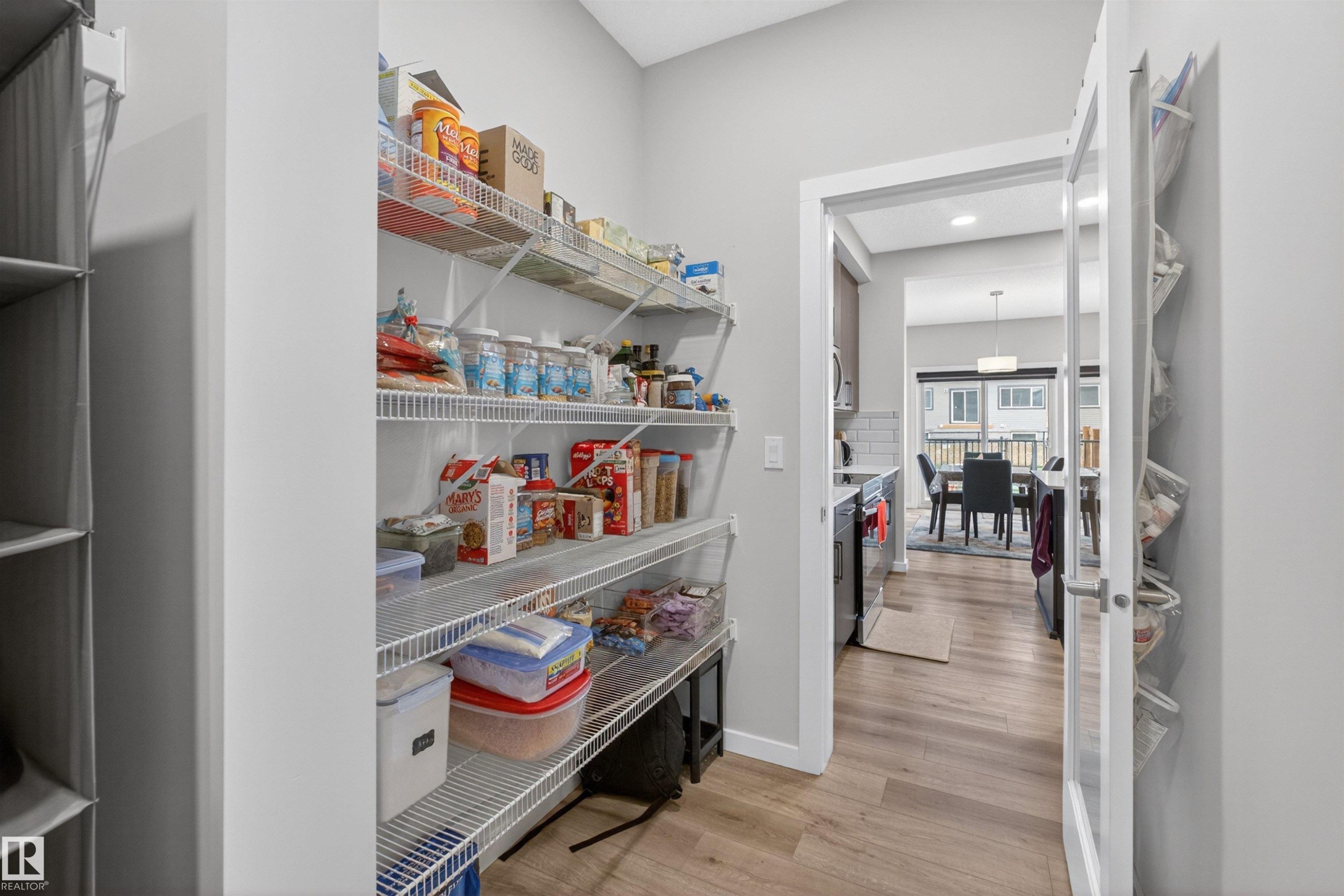 Walk-in pantry with wire shelving, light wood-finish flooring, and a glass-paneled door - 332 Juniper Cove, Leduc, AB - Indoor Photo Showing Other Room
