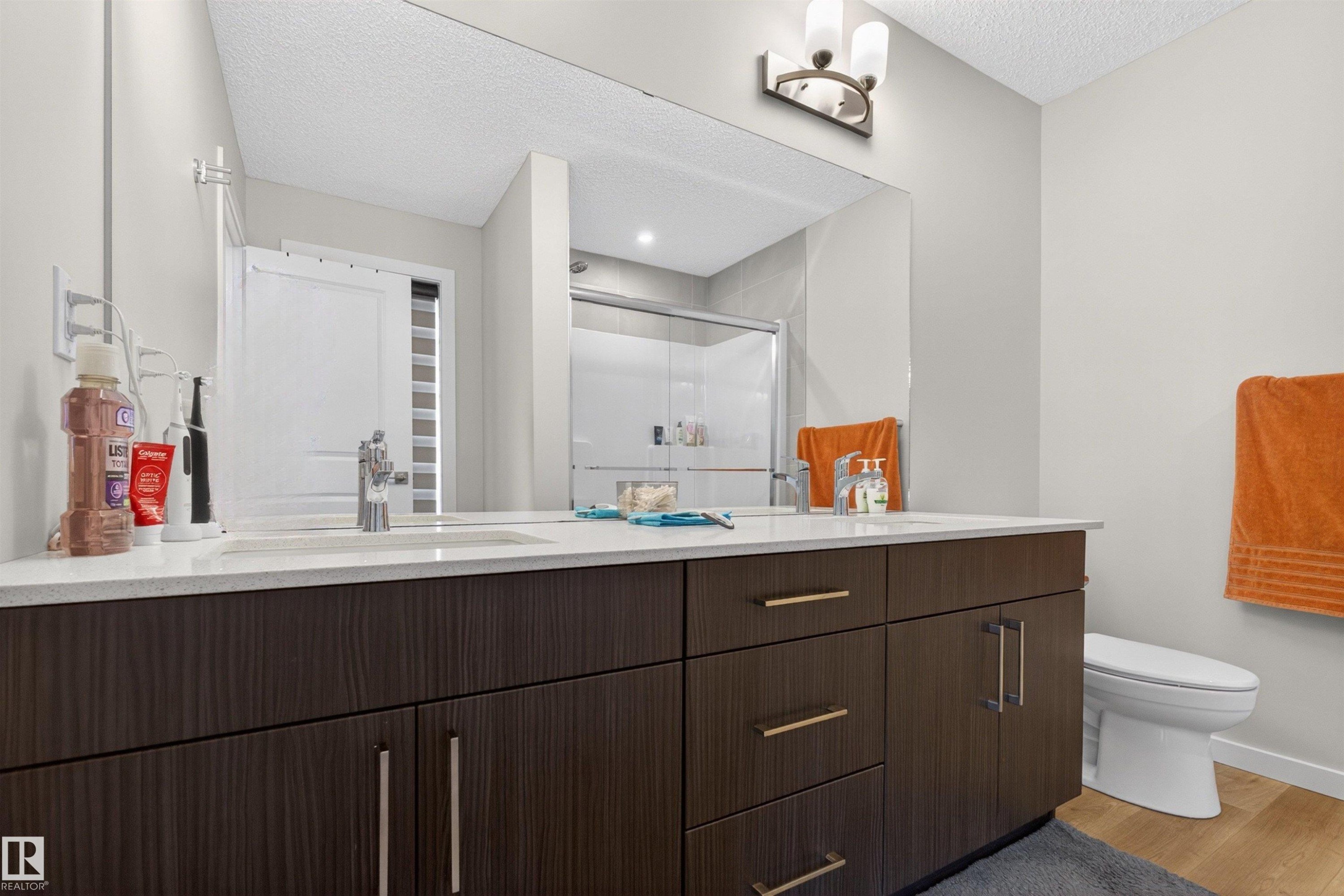 Double vanity with wood-finish cabinetry, quartz countertops, and chrome fixtures - 332 Juniper Cove, Leduc, AB - Indoor Photo Showing Bathroom