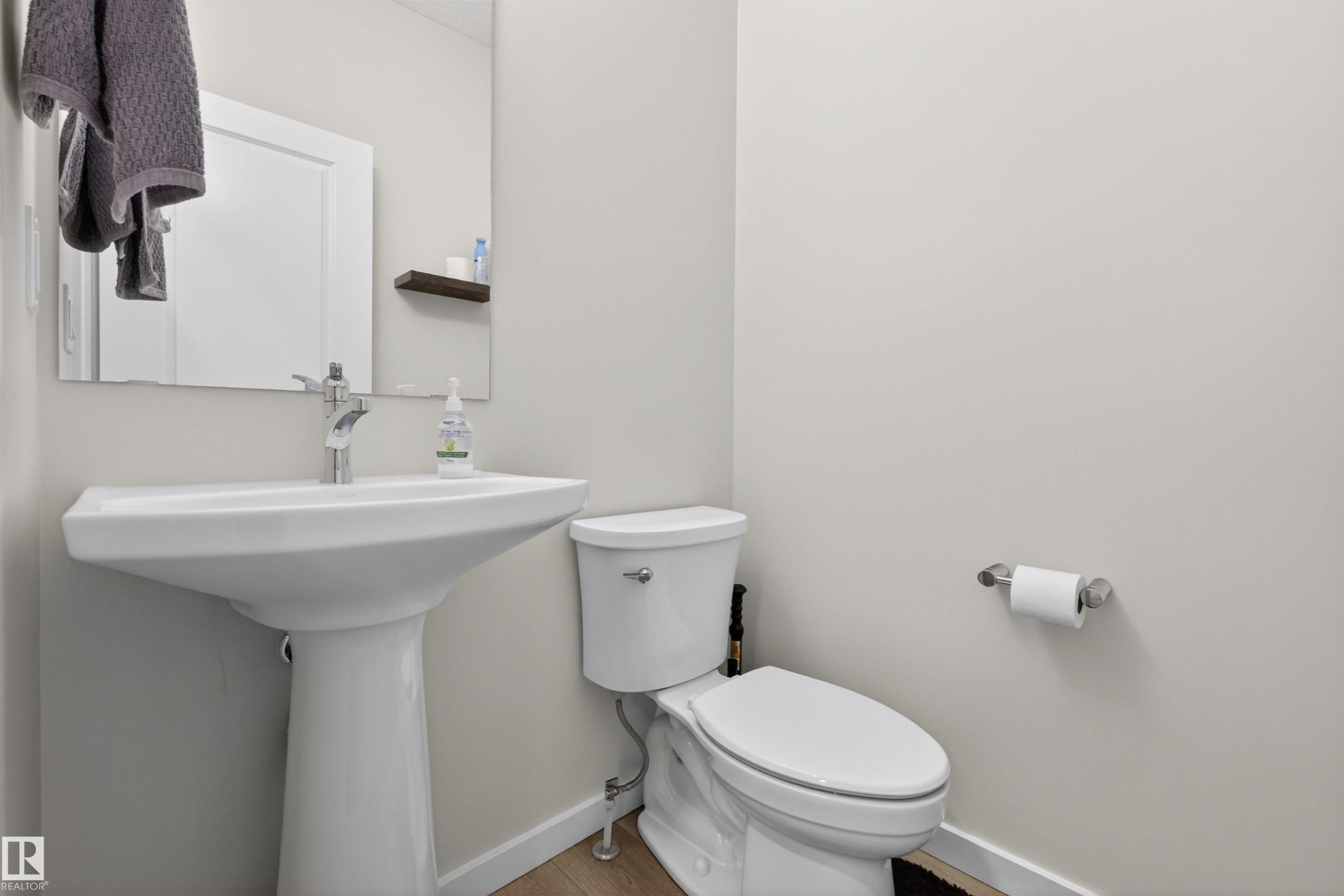 Modern bathroom featuring a white pedestal sink, chrome faucet, and a wall-mounted mirror - 332 Juniper Cove, Leduc, AB - Indoor Photo Showing Bathroom